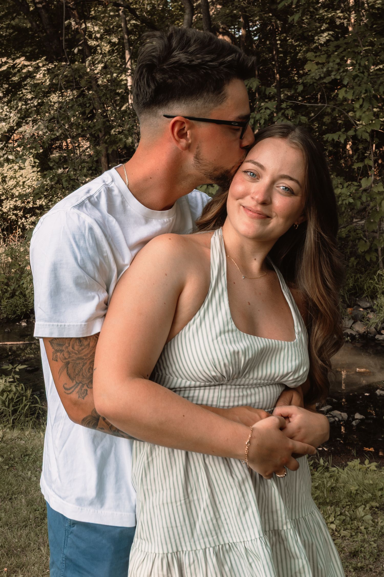 A couple shares tender moments in a garden setting while wearing casual summer attire.