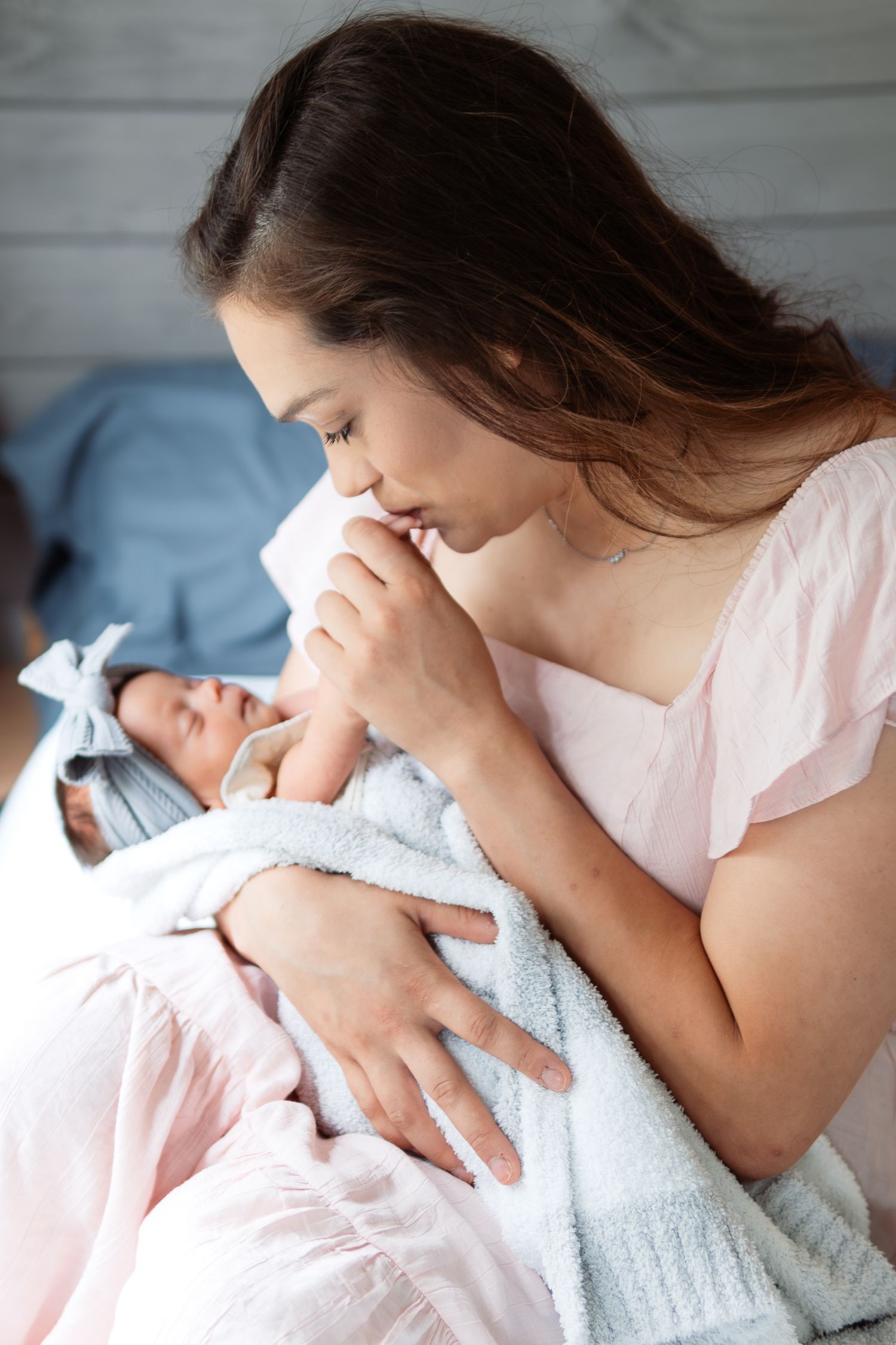 Tender nurturing moment shown in sequence as mother gently cradles and feeds newborn on blue bedding.