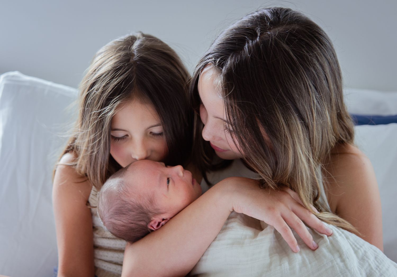Sequence of loving interaction between parent and newborn on light bedding.