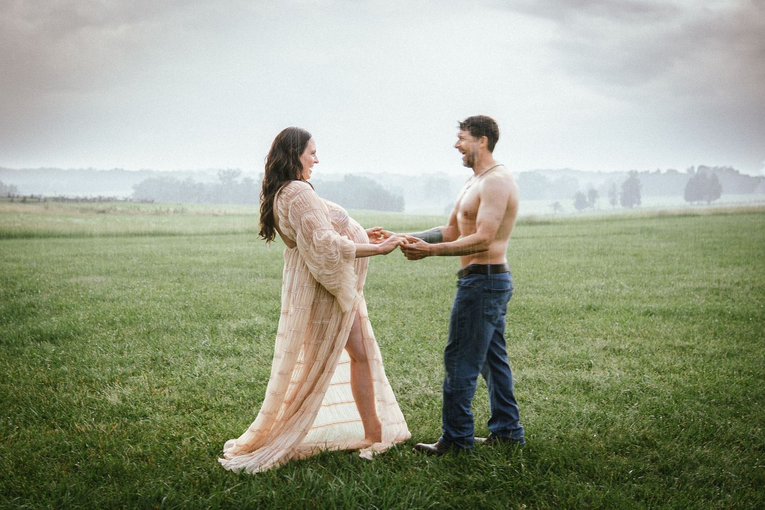 A couple stands together in a misty green field during a romantic outdoor photo session.
