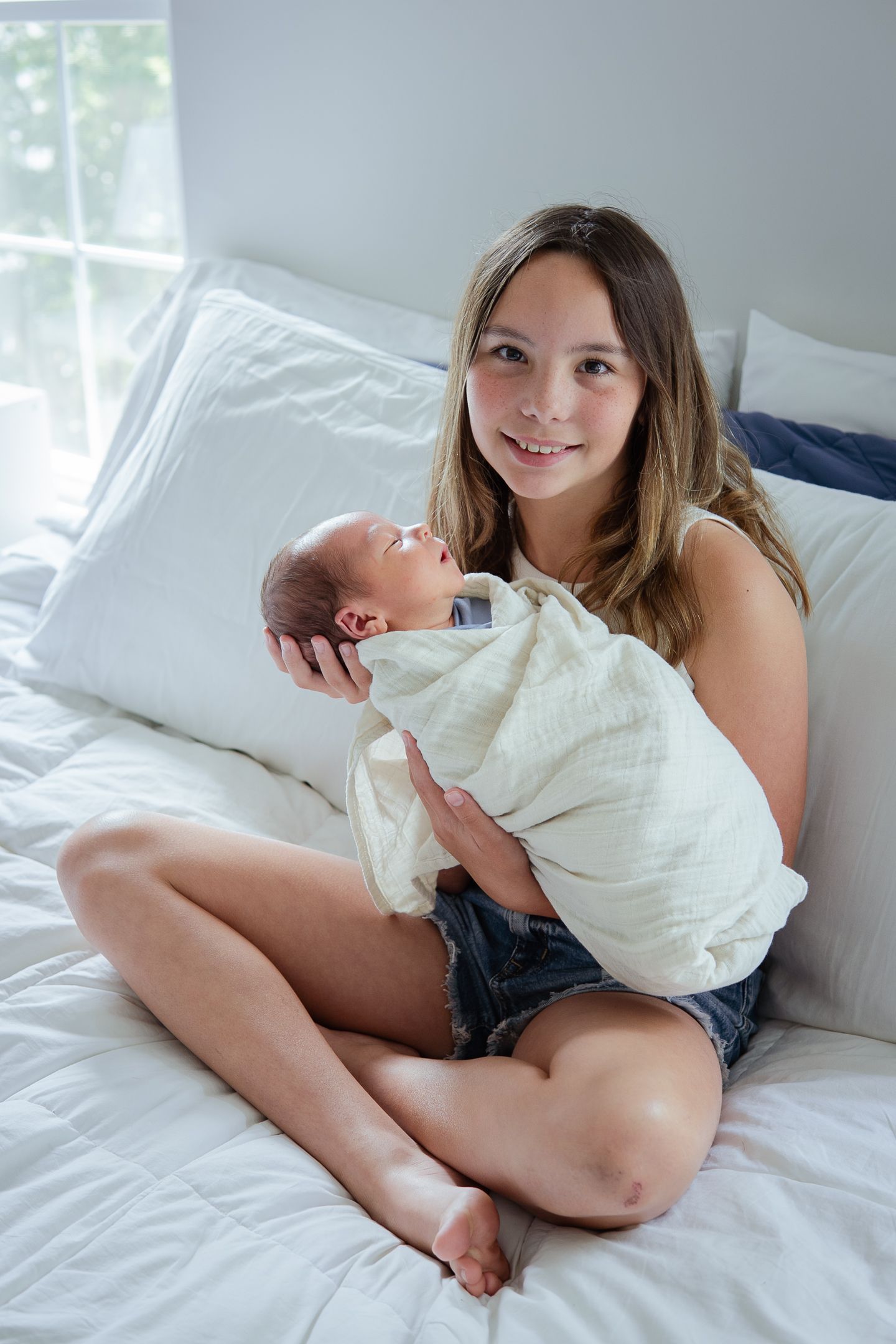 Relaxed lifestyle photos of parent and child sharing playful moments on a white bed.