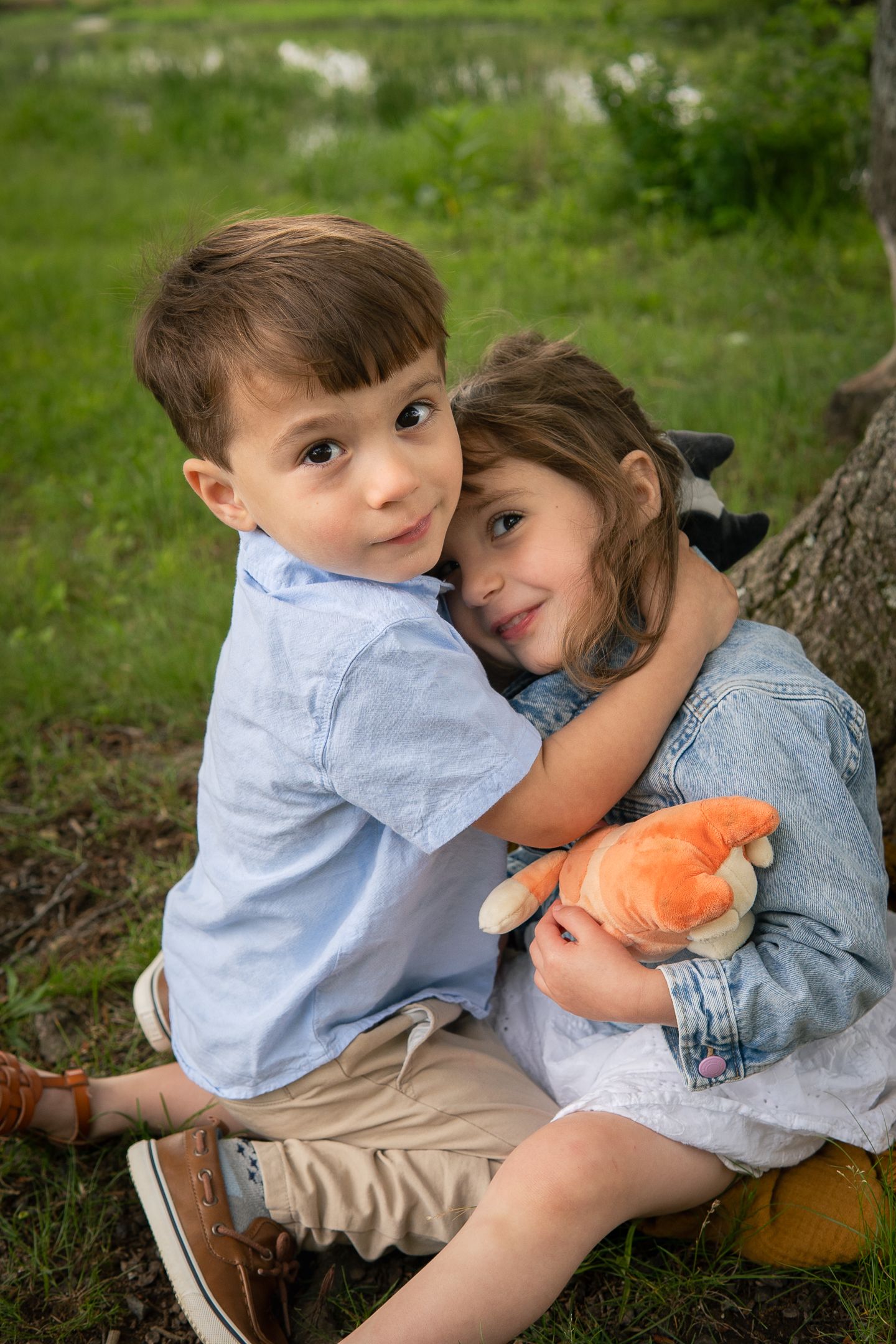 Heartwarming outdoor portrait with soft embraces and an orange toy on grassy ground.