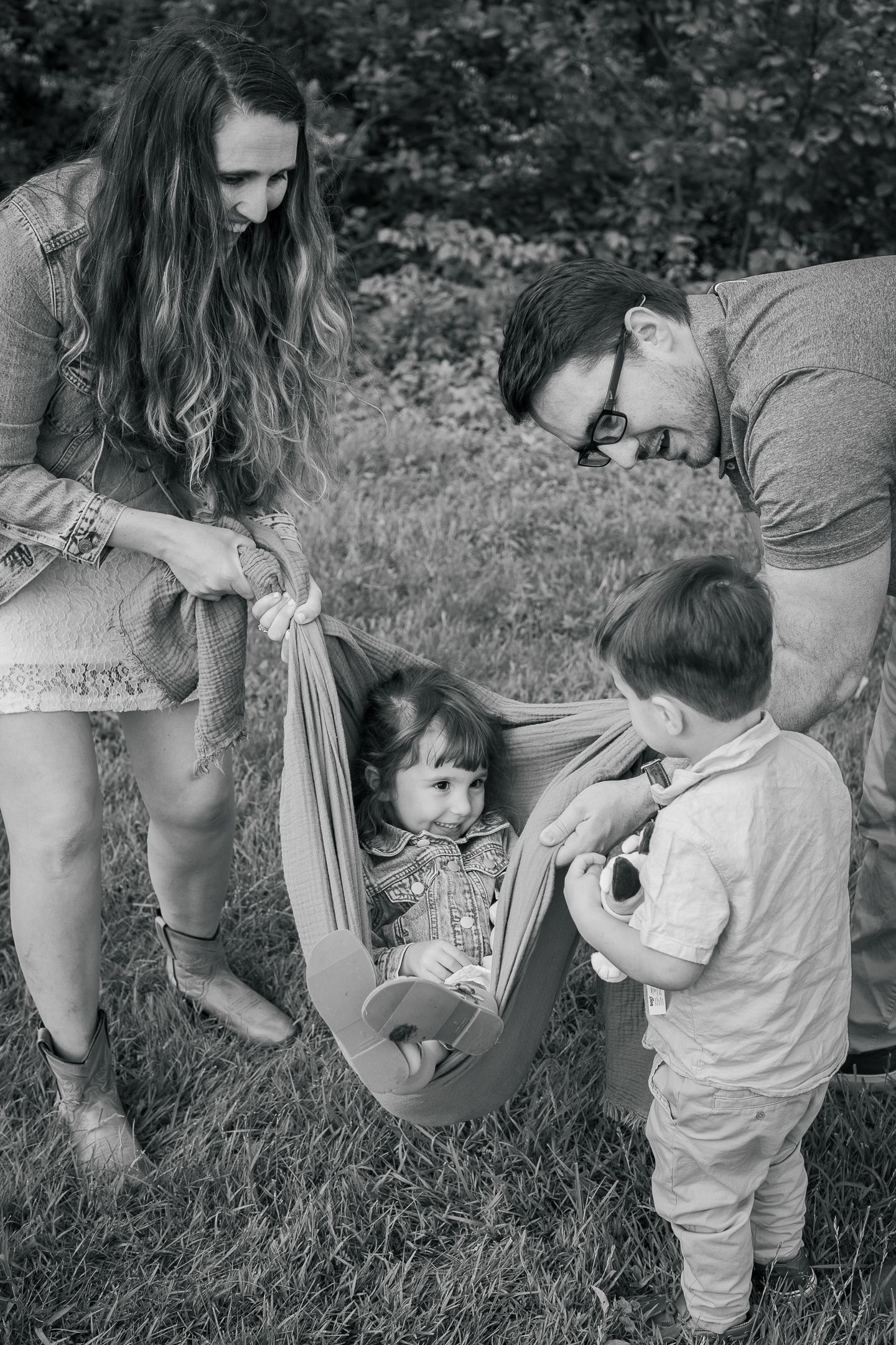 Four candid black and white photos show a toddler and caregiver interacting outdoors in a grassy area during playtime.