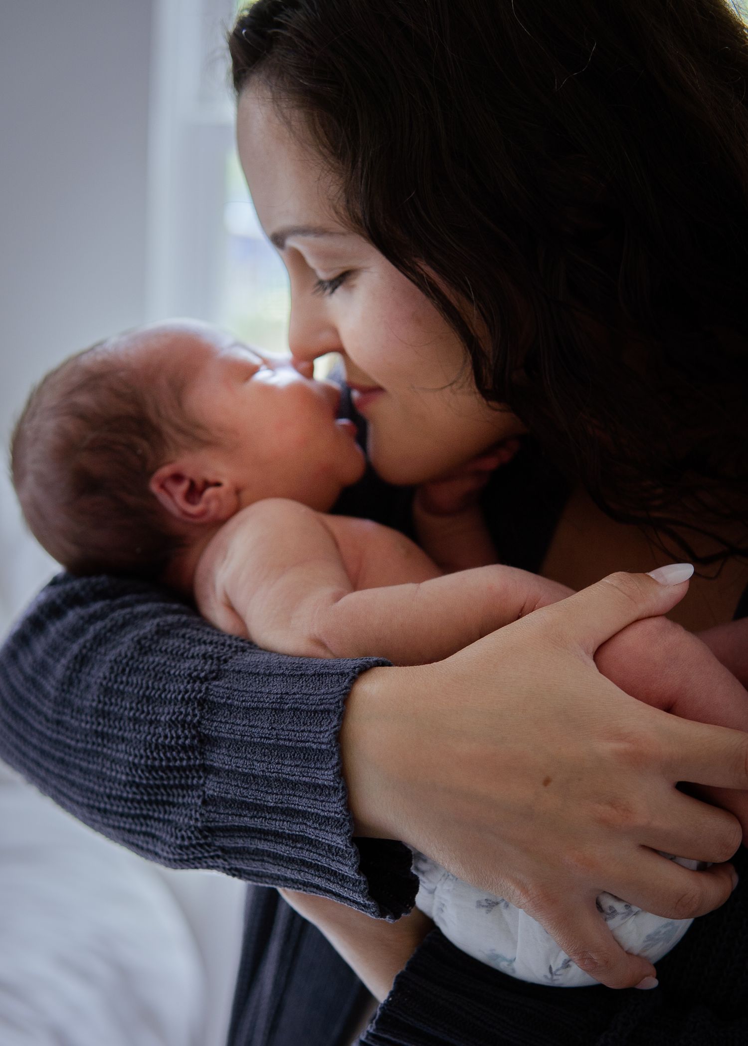 Intimate bonding moment between parent and sleepy newborn wrapped in cozy blanket.