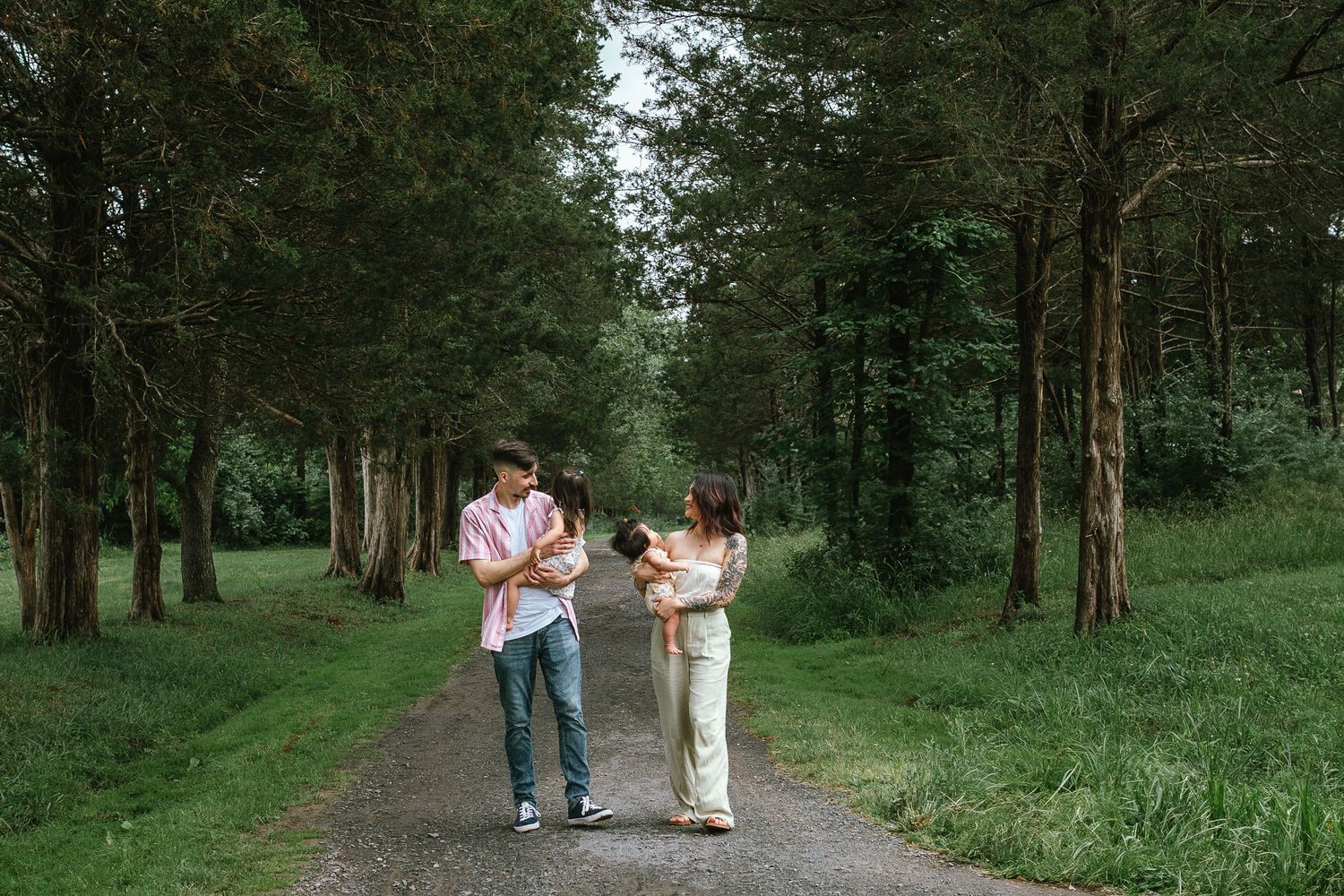 A family walking together on a tree-lined path through a serene forest setting.
