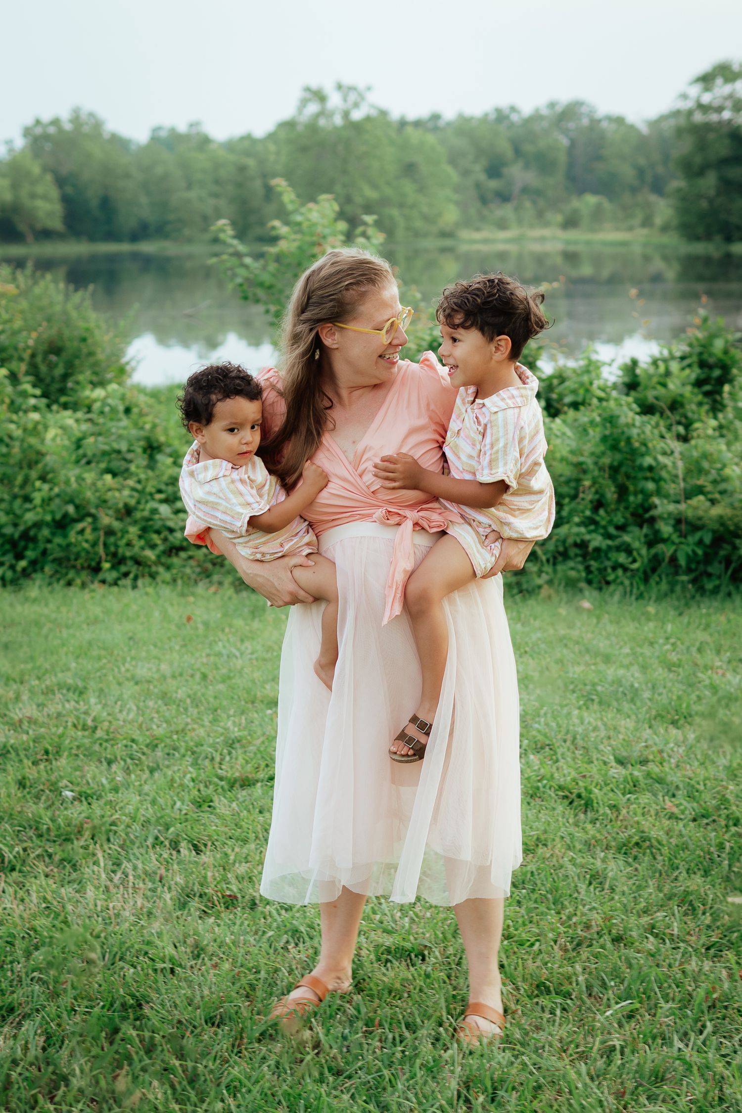 Family in coordinated outfits posing by a lake with lush greenery in the background.