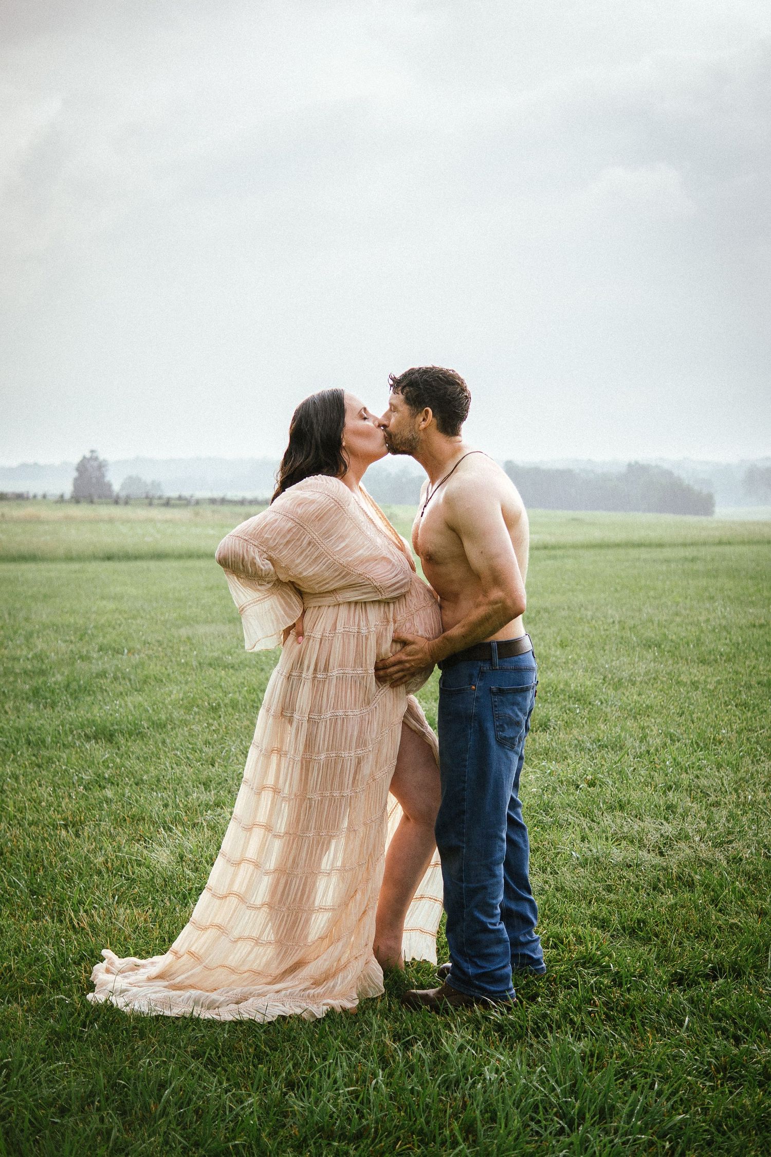 A romantic couple embraces in a misty field, with the woman wearing a flowing beige dress.