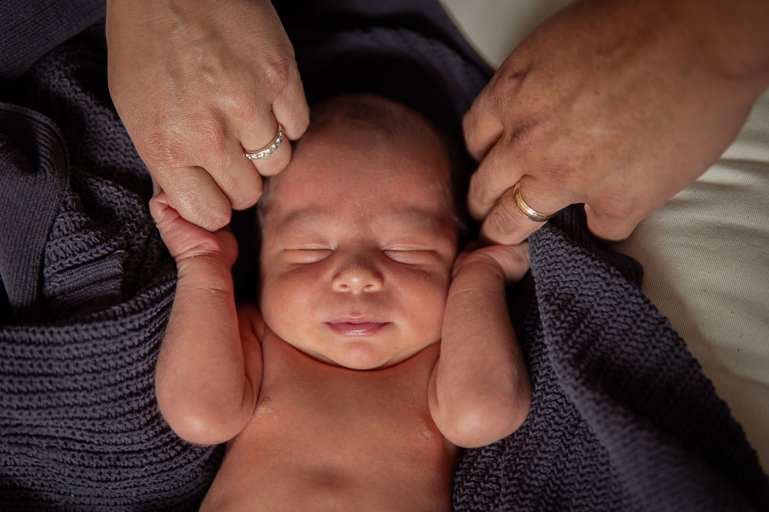 Intimate photography sequence showing sleeping newborn swaddled in dark knit fabric.