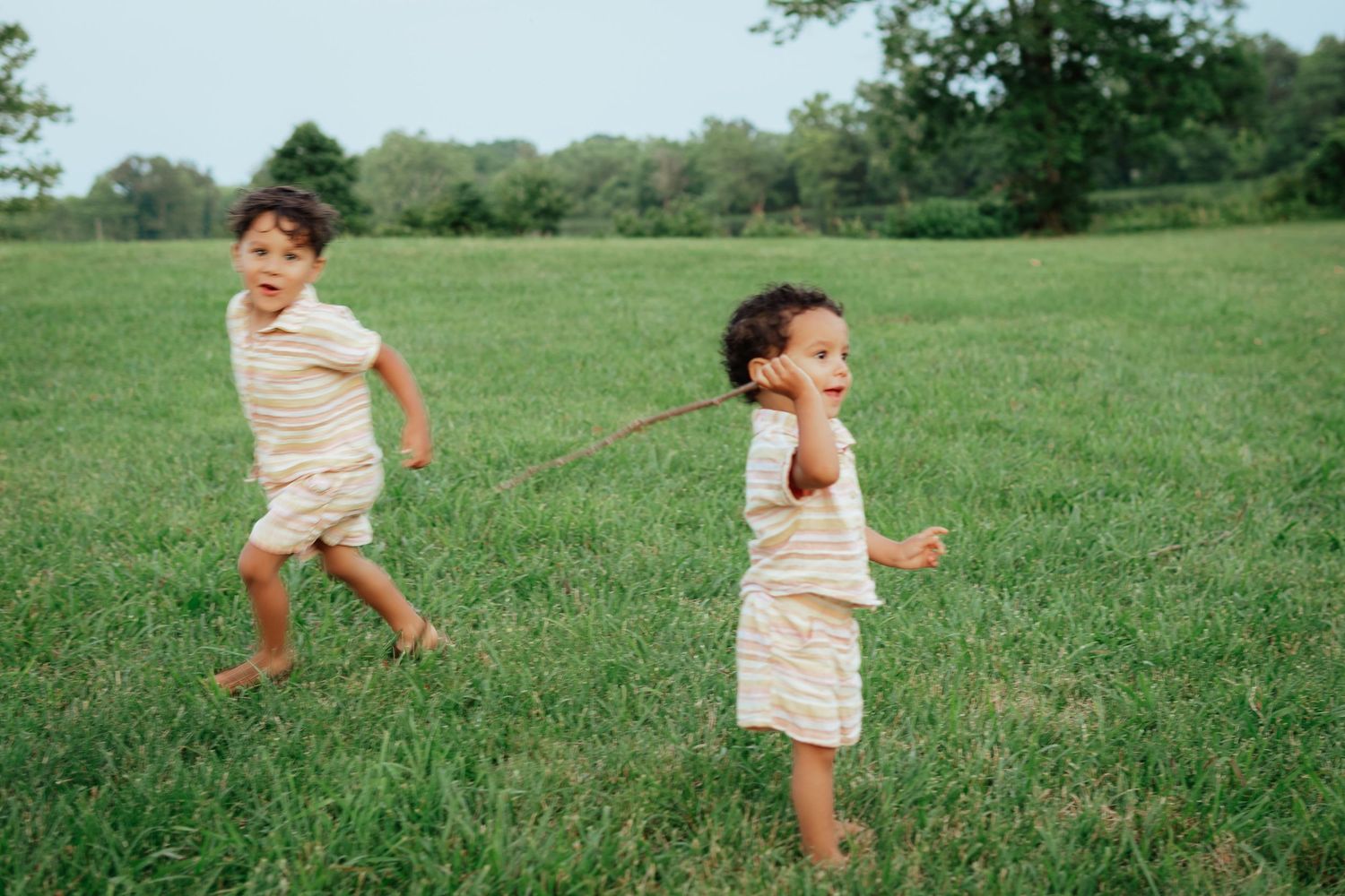 Energetic children running and playing together in an open grassy field on a sunny day.