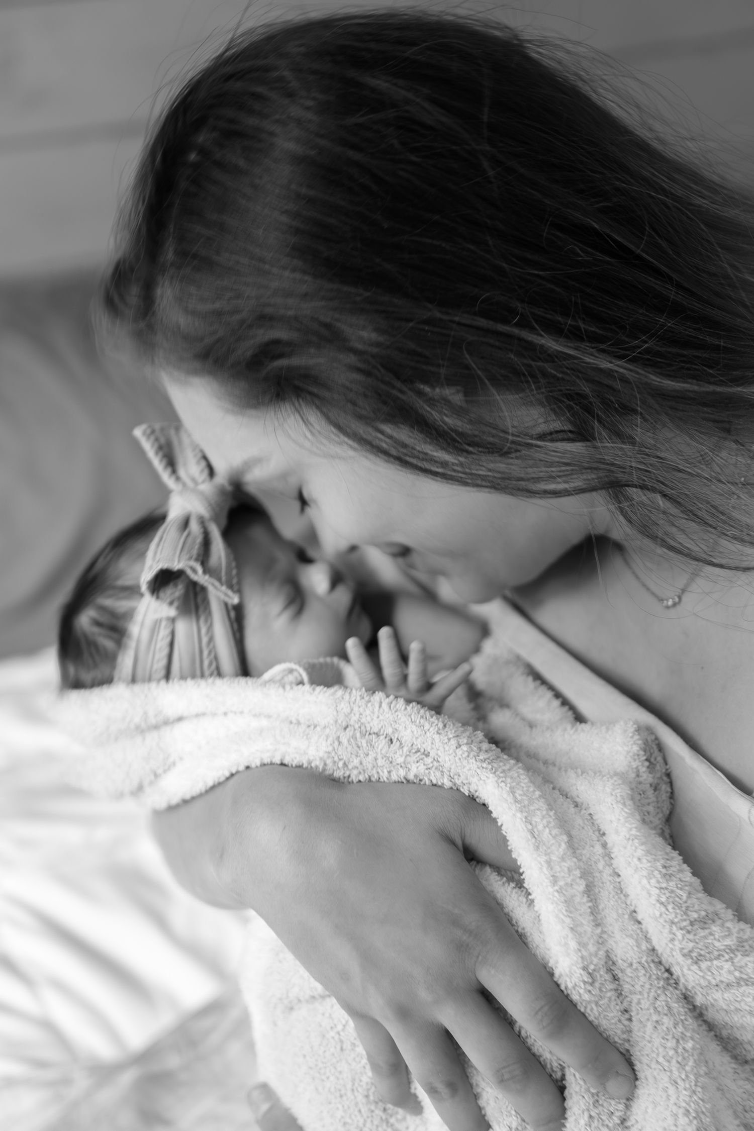 Black and white series showing intimate mother and baby bonding moments with soft blankets.