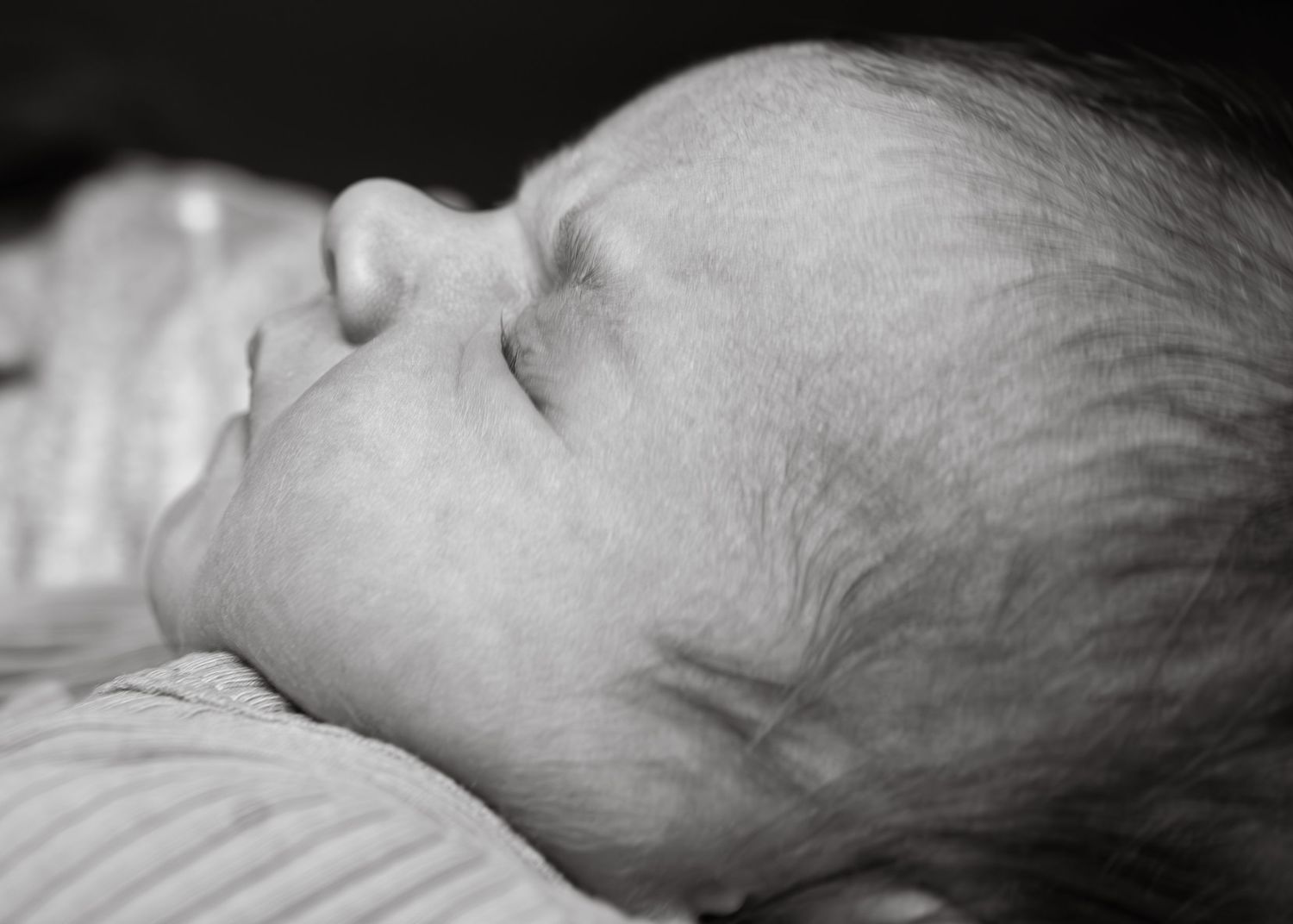 A black and white close-up photograph showing a newborn baby's delicate facial features in profile.