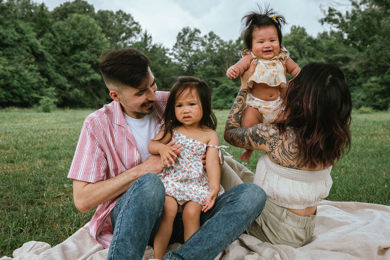 A family having a picnic on a blanket in a lush green field on a sunny summer day.
