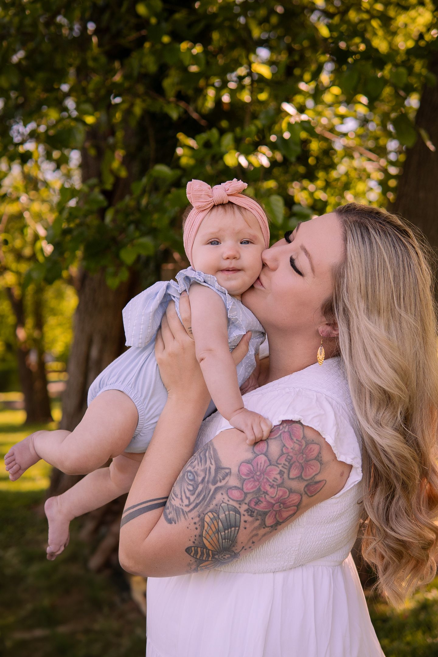 Tender outdoor portrait of parent and baby sharing affectionate moment in natural lighting.