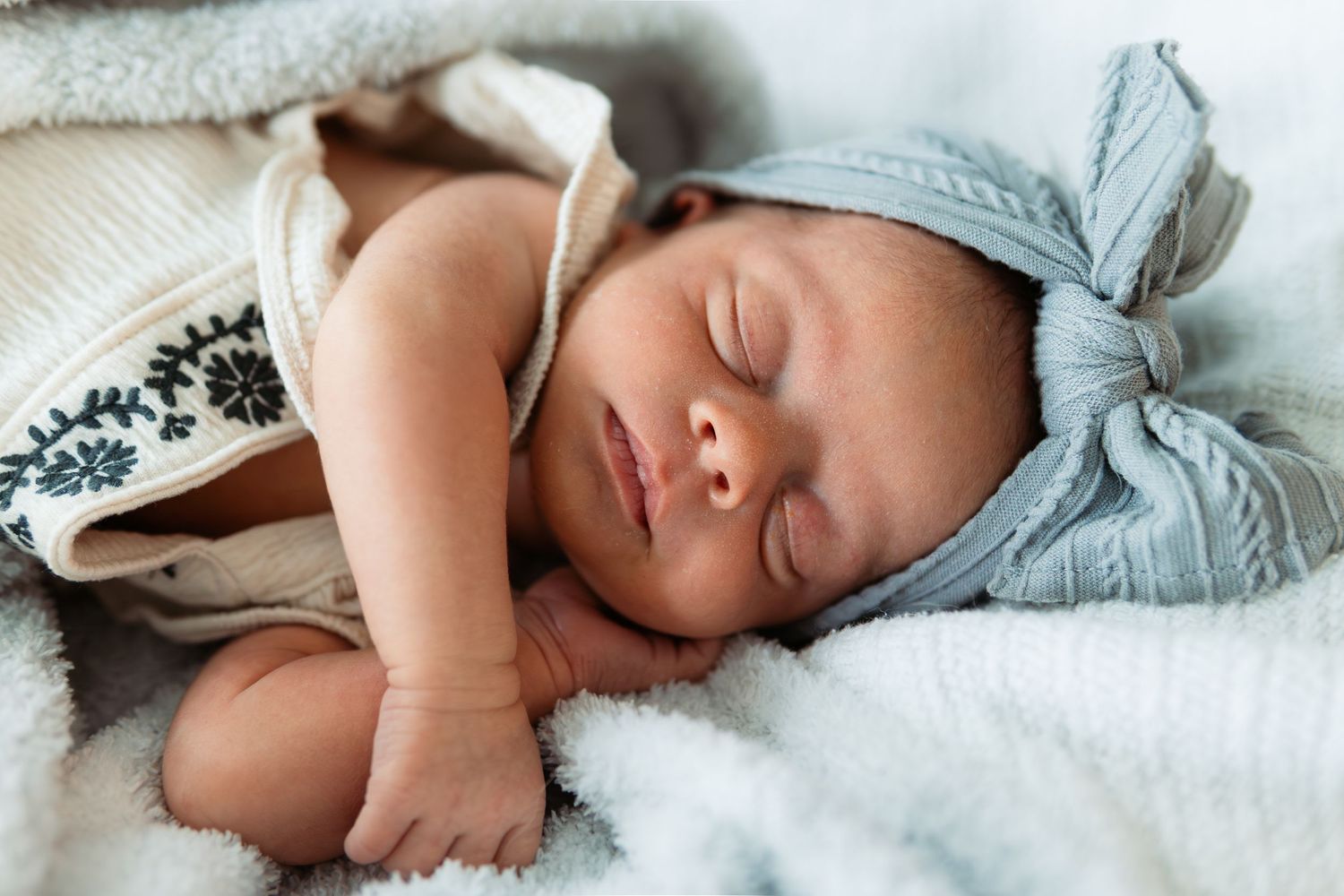 Peaceful sleeping newborn wrapped in soft blue blanket.