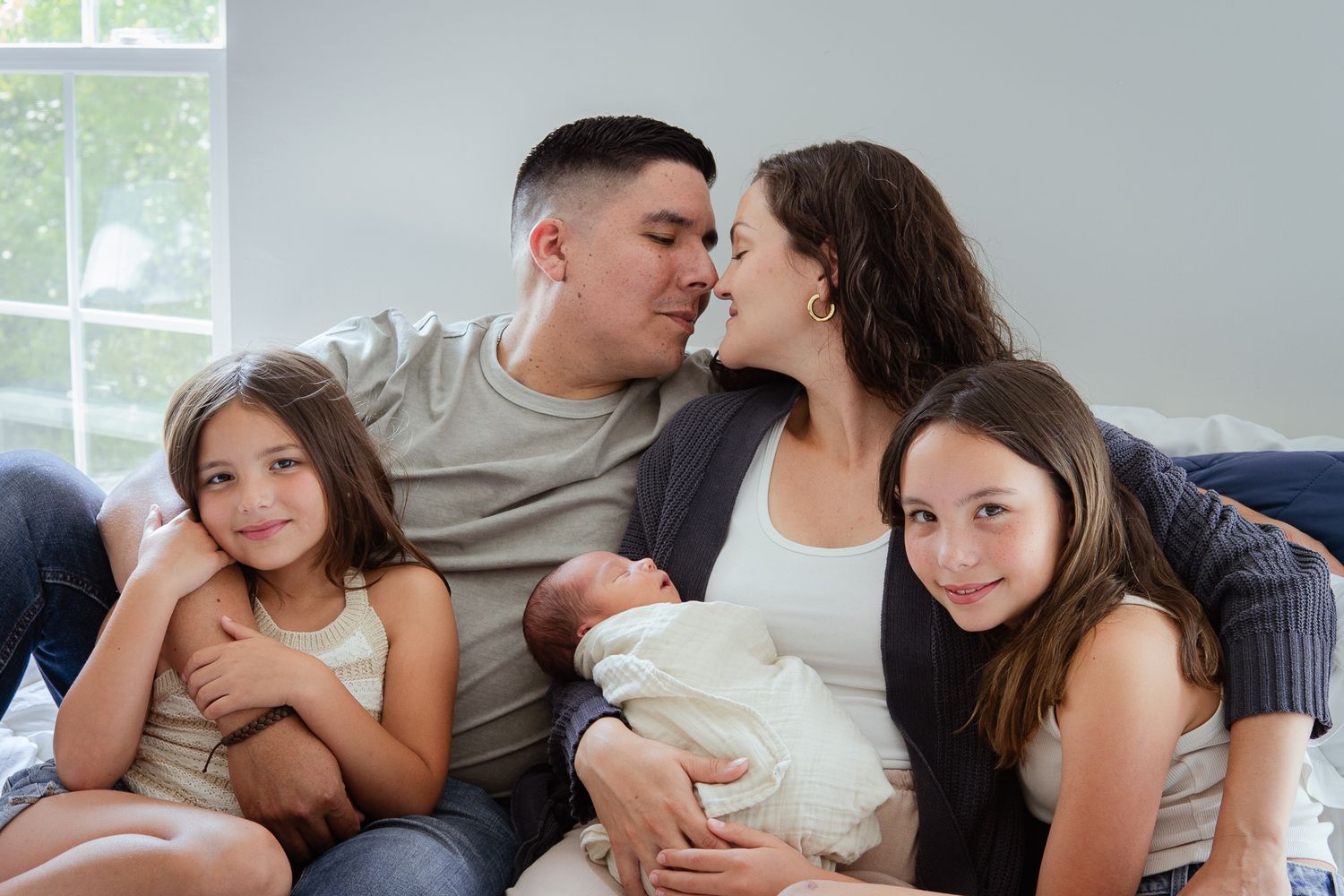 Candid family portrait with newborn baby showing intimate connection.