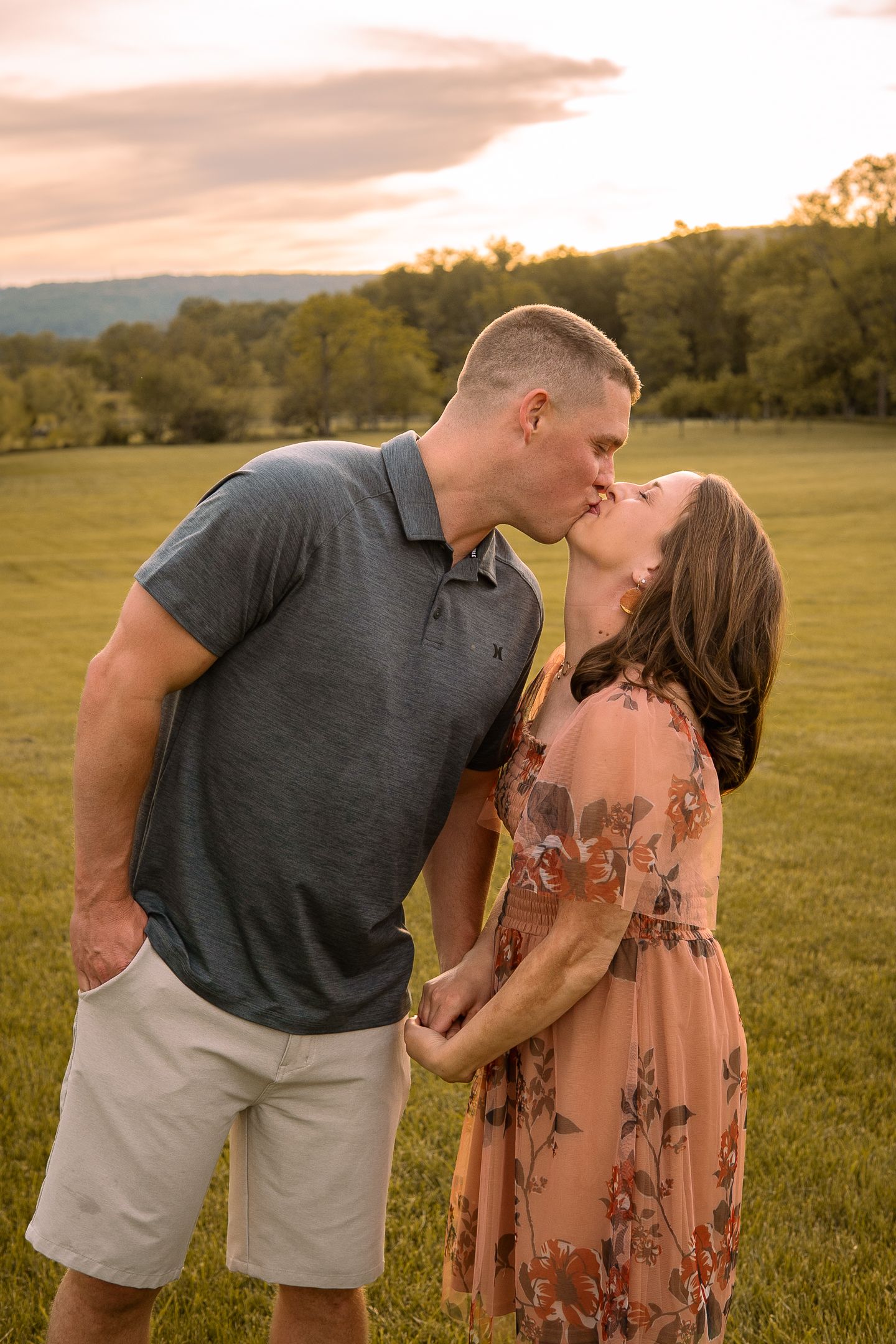 A romantic sunset moment captured in a grassy field with mountains and autumn trees in the background.