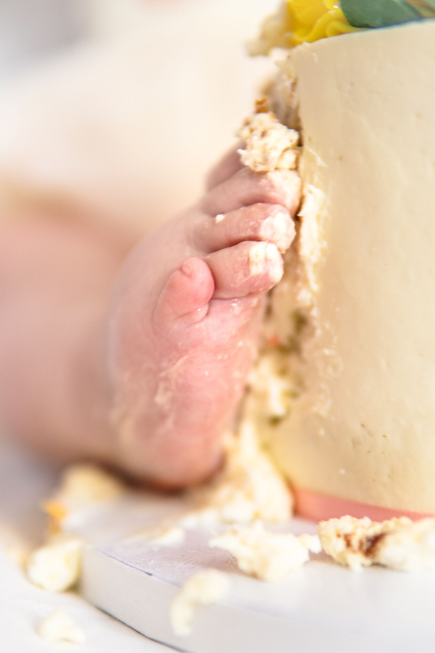 Close up of tiny toes touching white birthday cake during first birthday cake smash photo session.