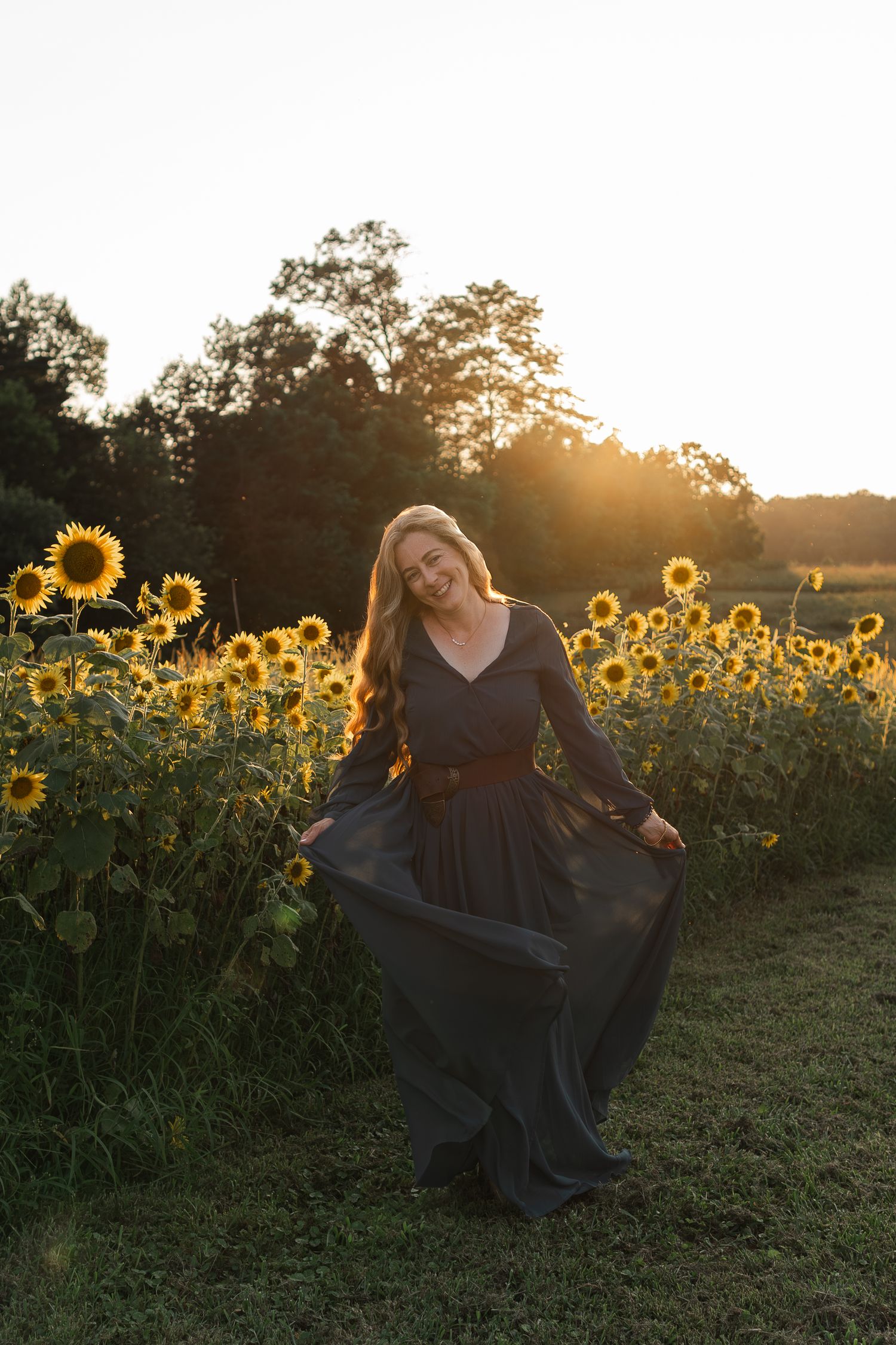 A dreamy sunset photoshoot in a sunflower field with flowing dress movement and golden backlight.