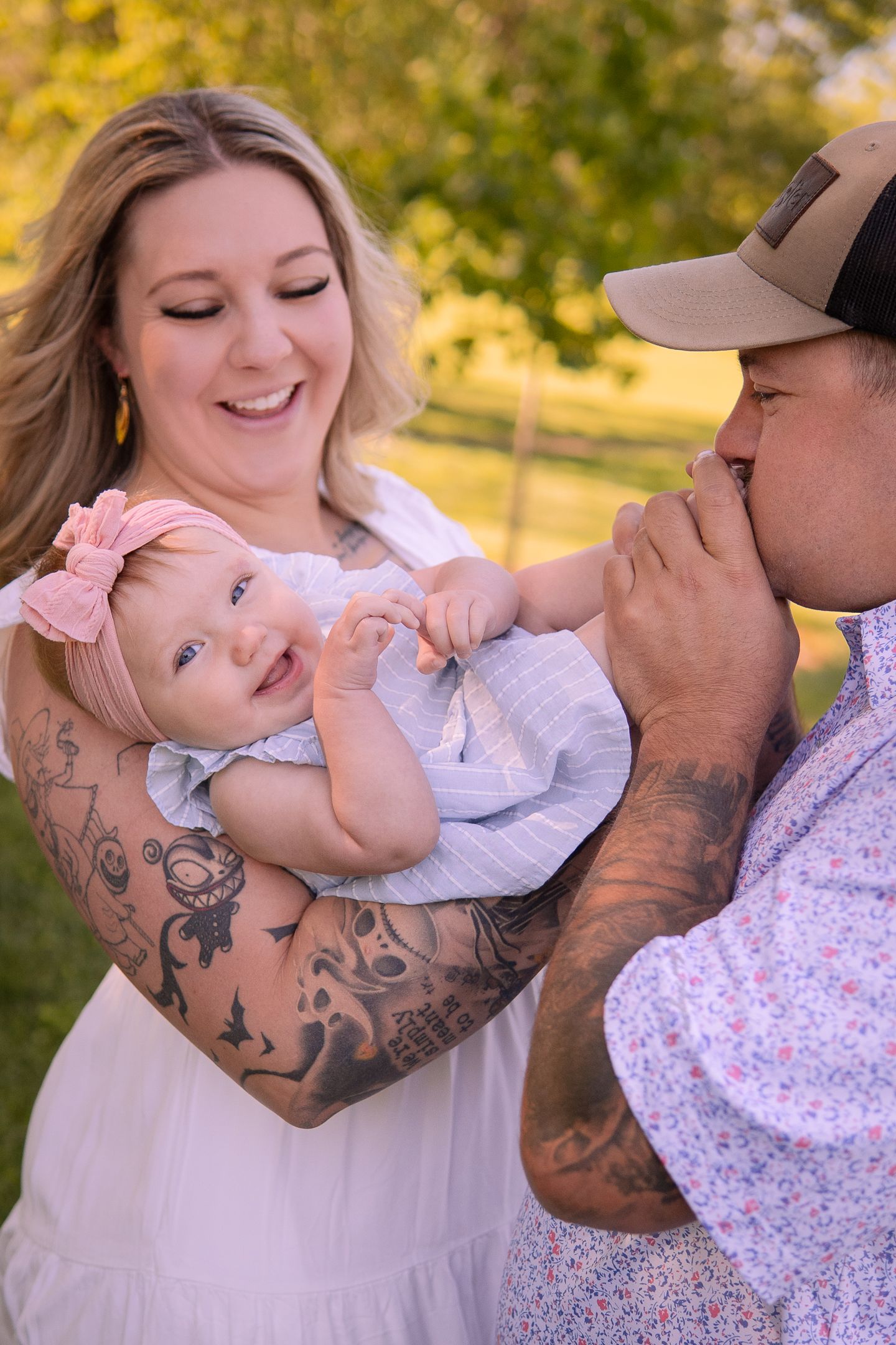 Family plays with baby showing tender moments in outdoor portrait session.