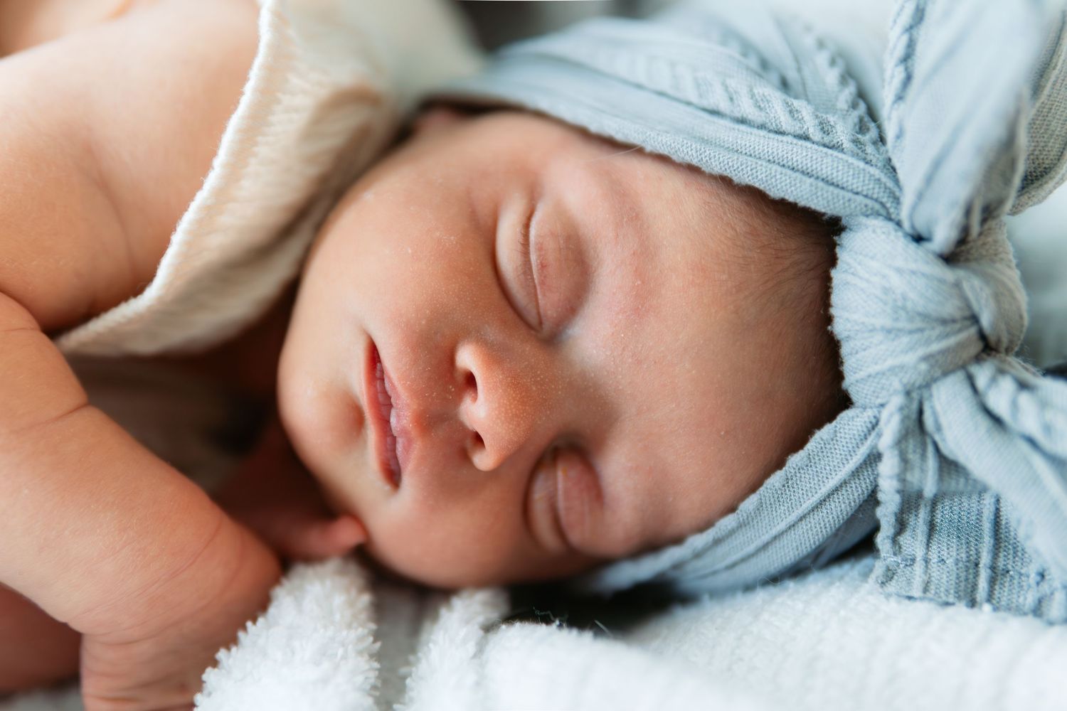 Newborn baby sleeping peacefully in soft blue swaddle blanket.