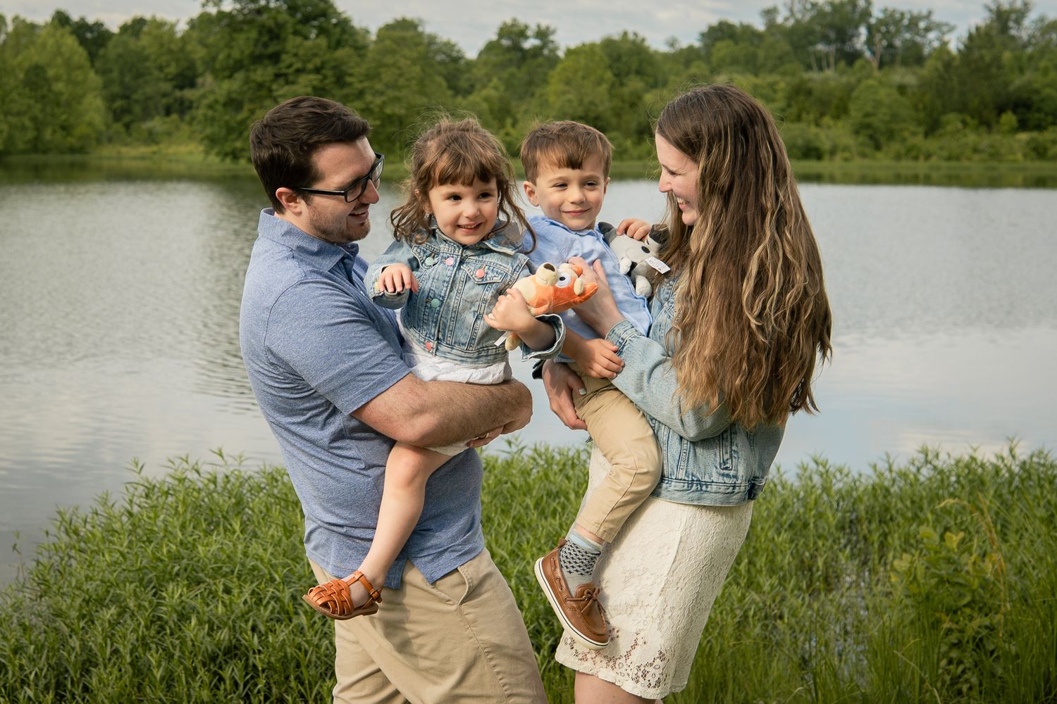A family shares a joyful moment together by a serene lake on a sunny spring day.