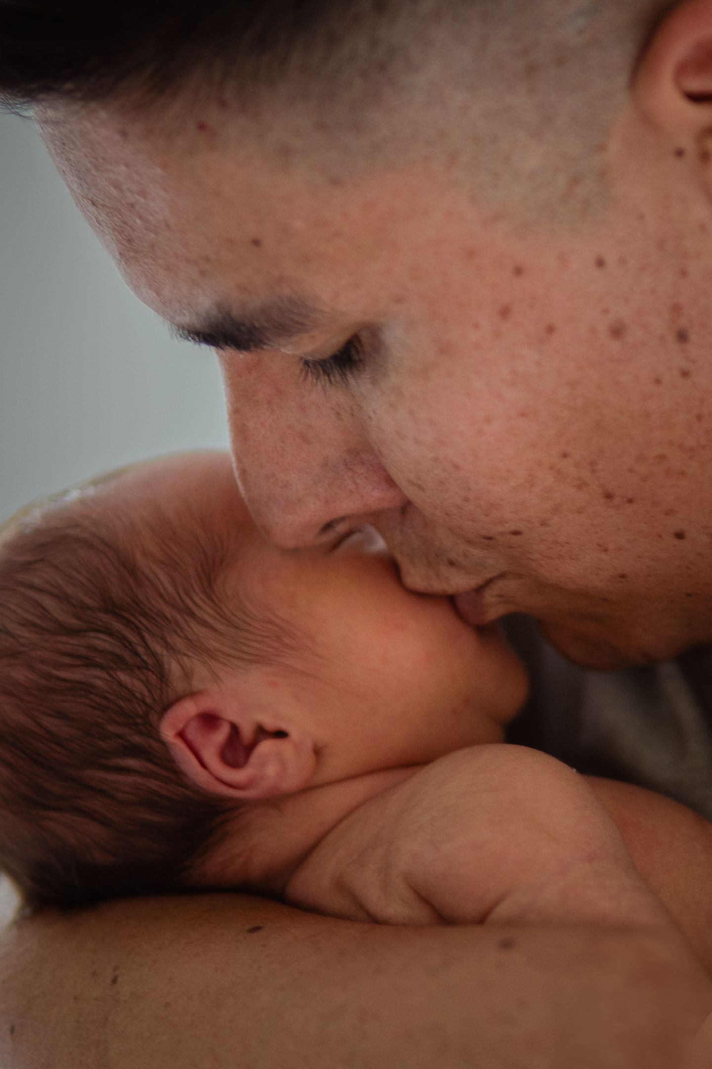 An intimate moment between parent and newborn baby in soft natural light.