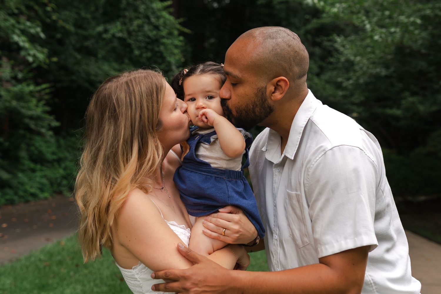 Affectionate family enjoying tender moments together in an outdoor setting with soft natural lighting.