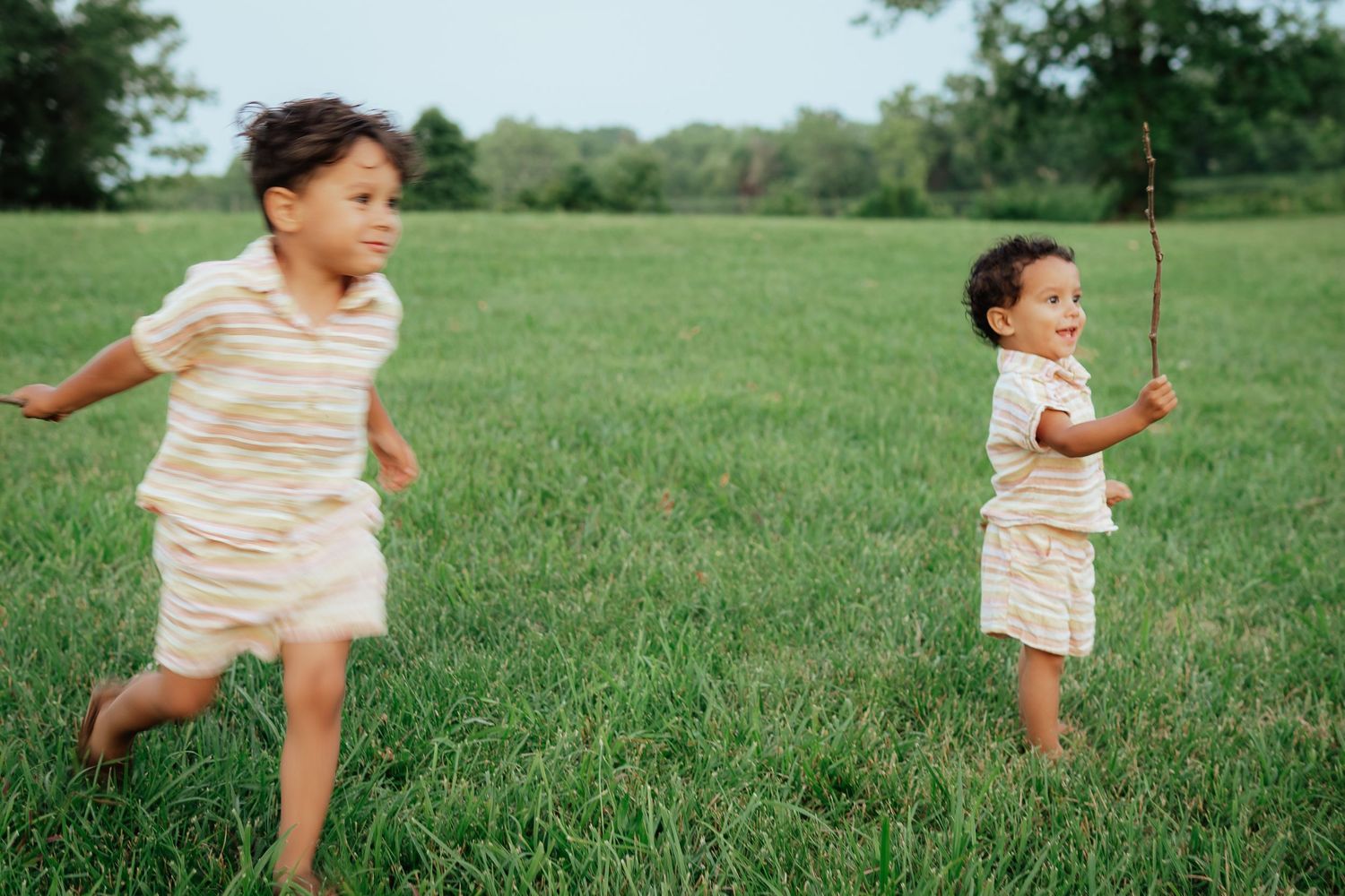 Two children running and playing in a grassy field.