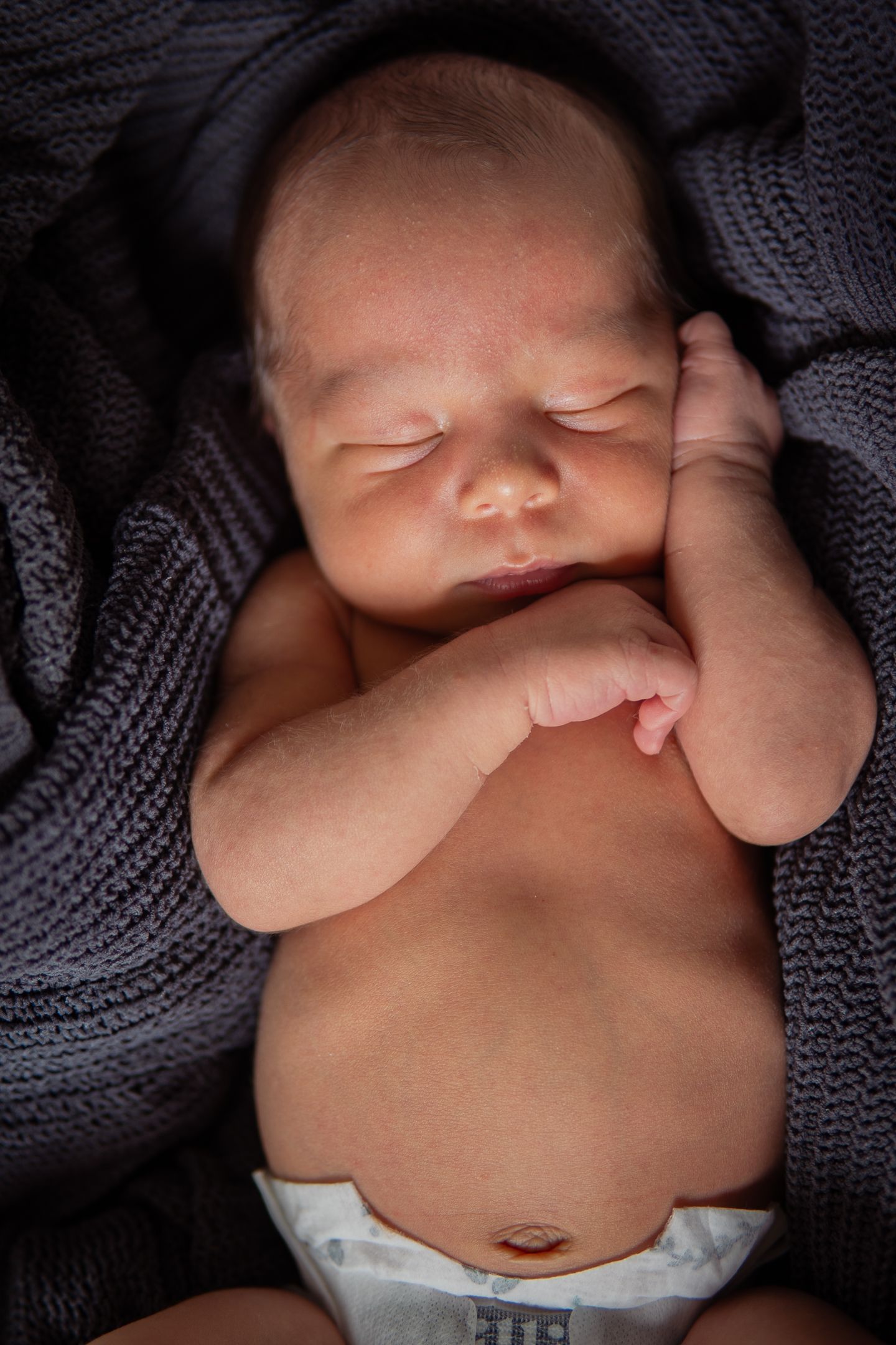 Series of gentle newborn close-up portraits wrapped in gray knit fabric.