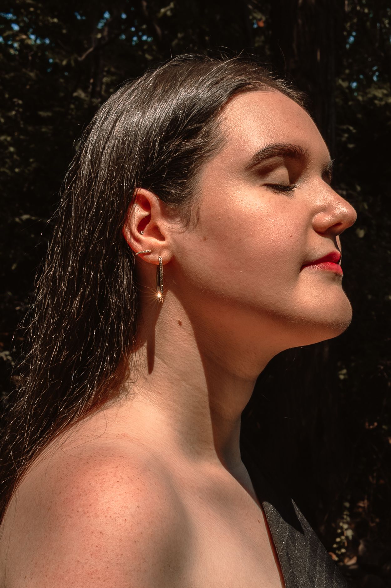 A series of profile portraits showing someone tilting their head back against a dark forest background in dramatic lighting.