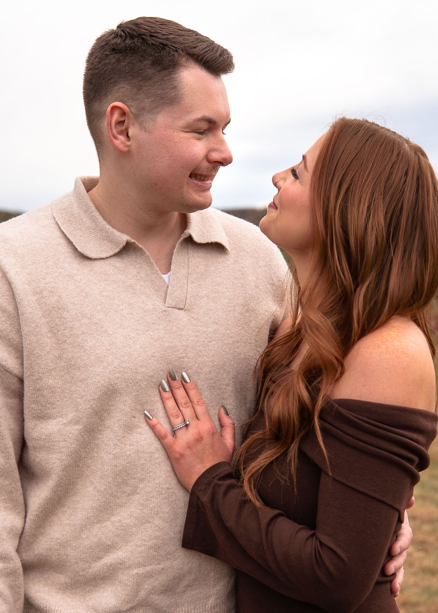 A couple shares a joyful moment together in a series of romantic engagement photos outdoors.