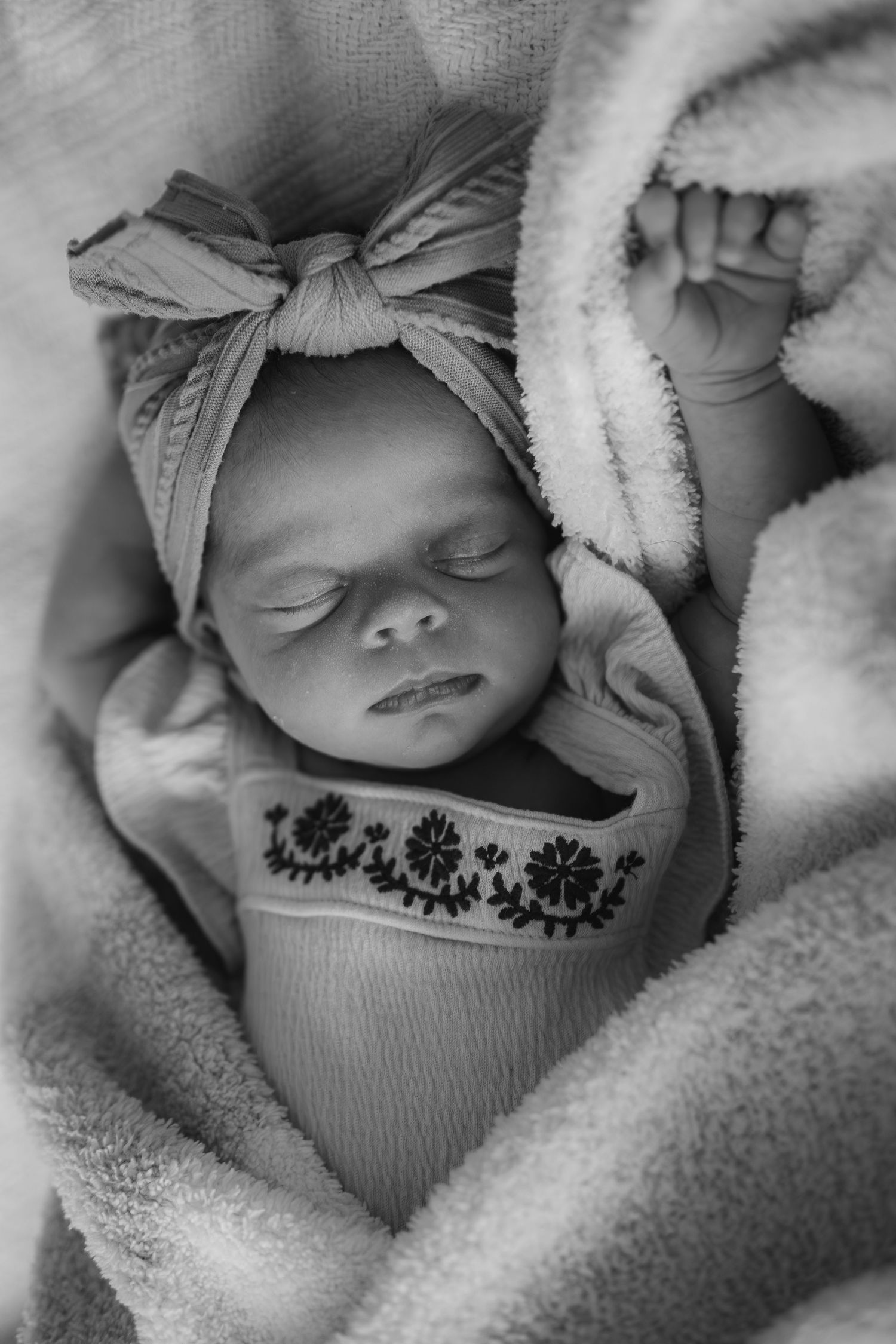 Series of black and white images showing a sleeping newborn swaddled in soft blankets with decorative markings visible.