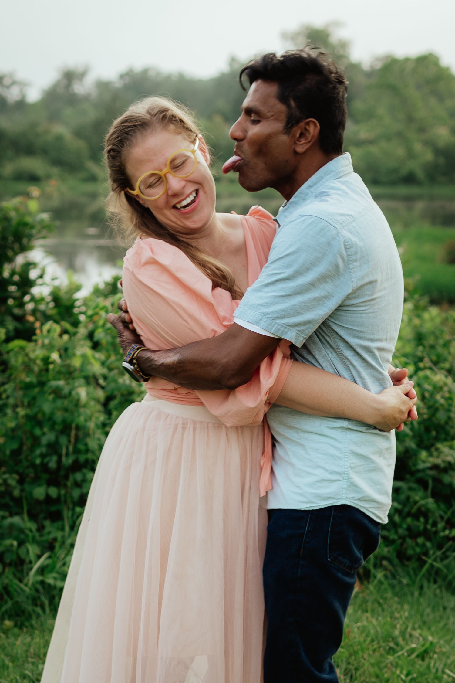 Couple sharing a candid laughing moment together in a garden setting.