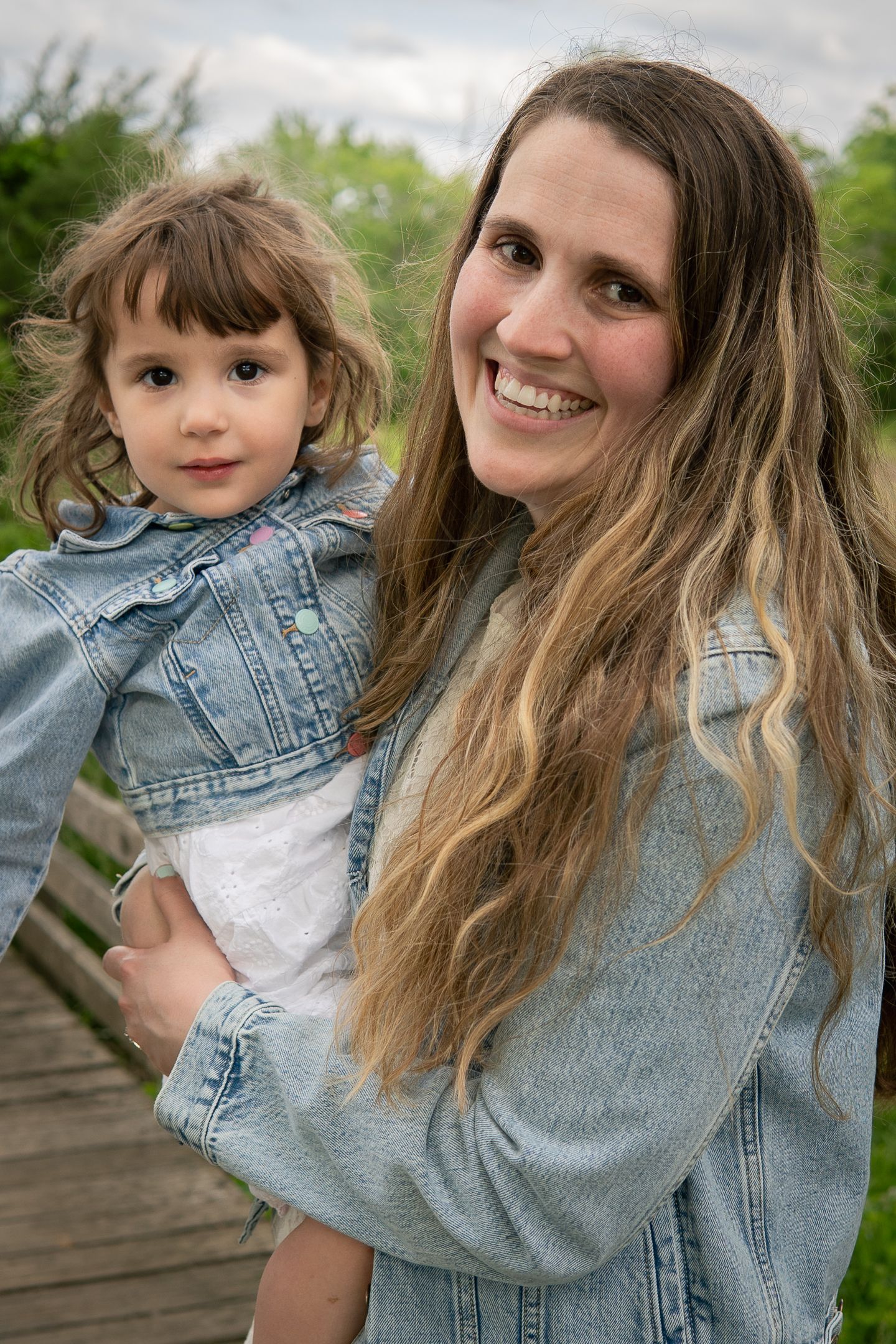 Sweet outdoor photo session showing playful interactions between parent and child wearing matching denim jackets.