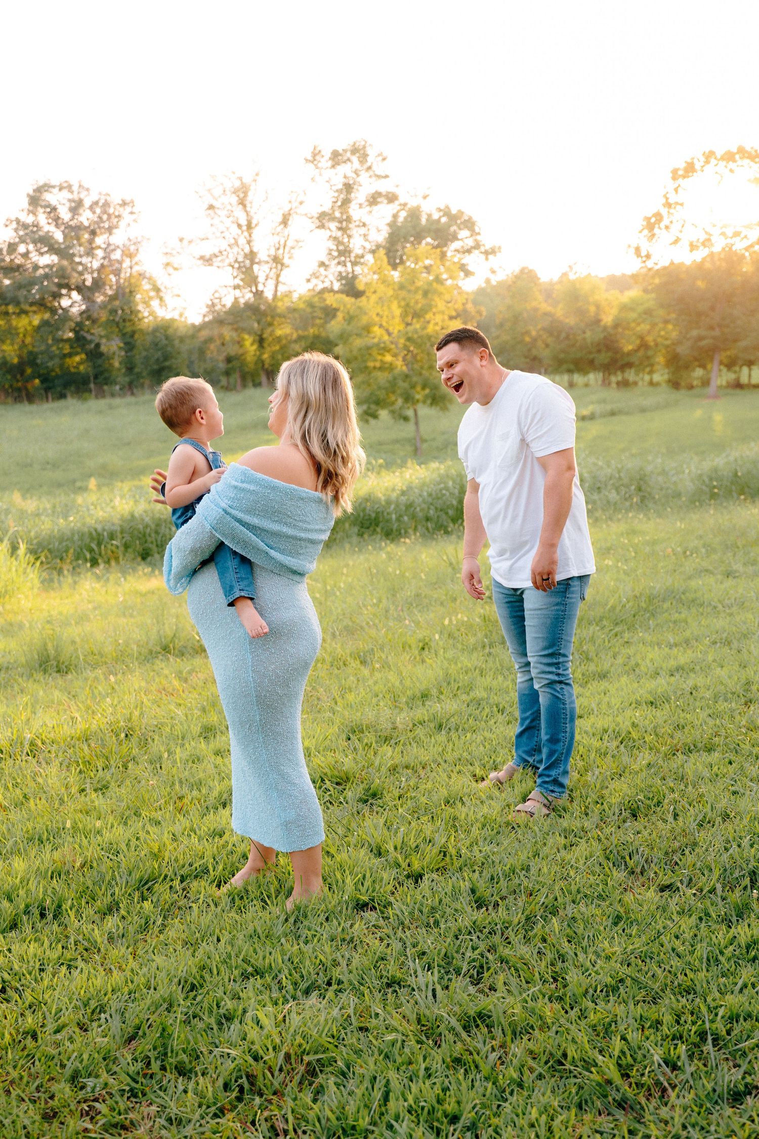 Playful family photos in a grassy field during golden hour.