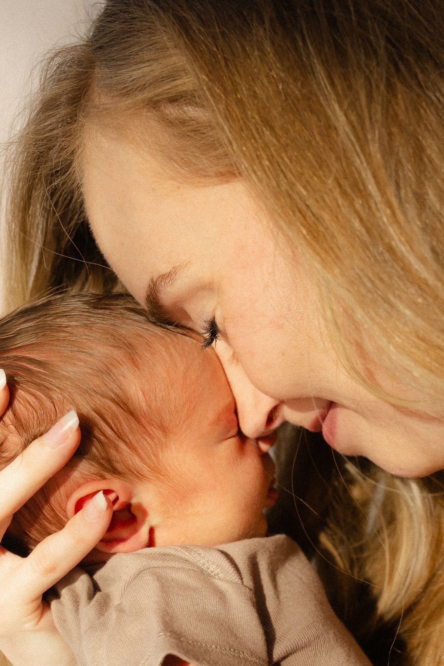 A loving mother tenderly touches noses with her newborn baby, sharing an intimate bonding moment.