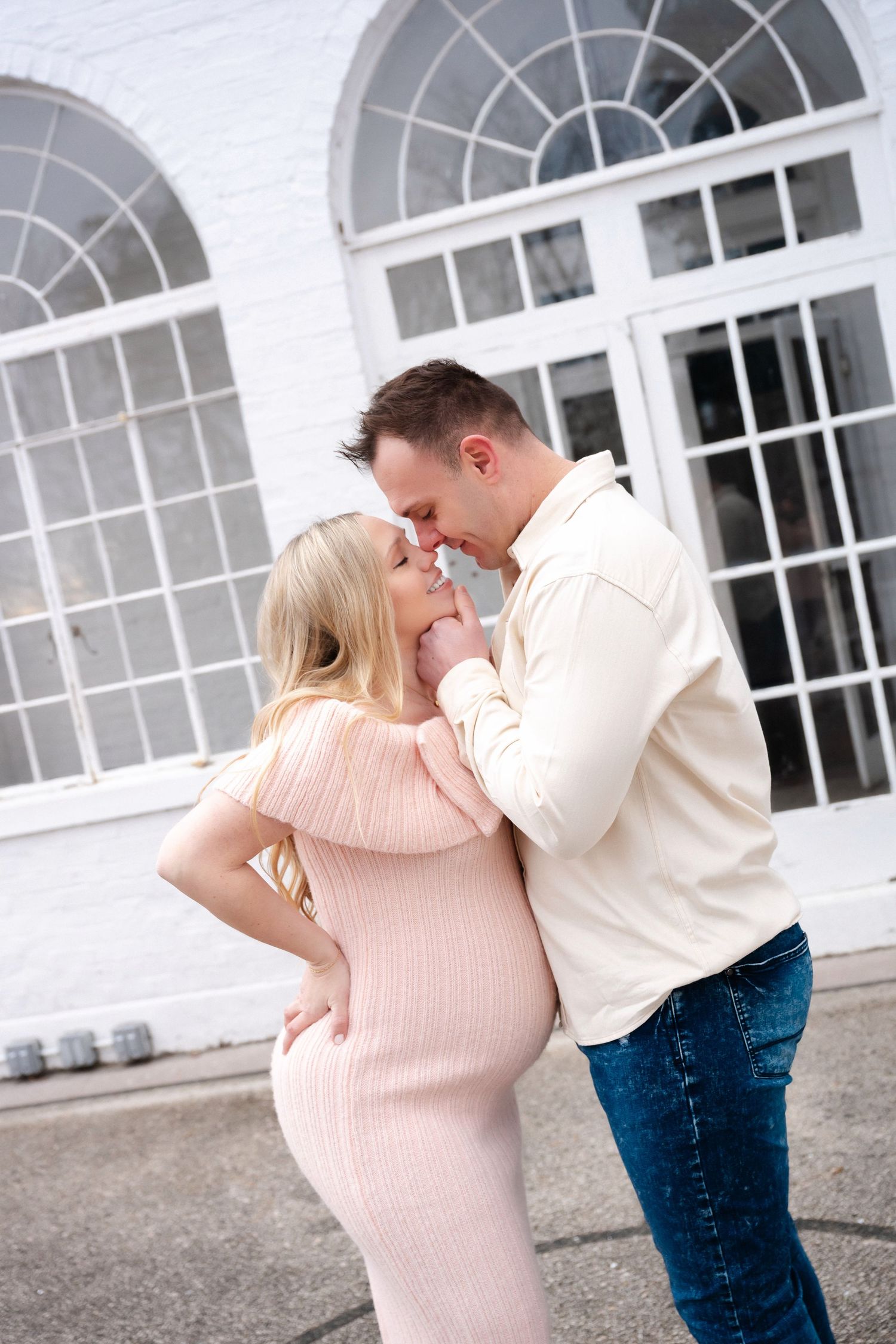 A tender moment captured in front of a white building with arched windows.