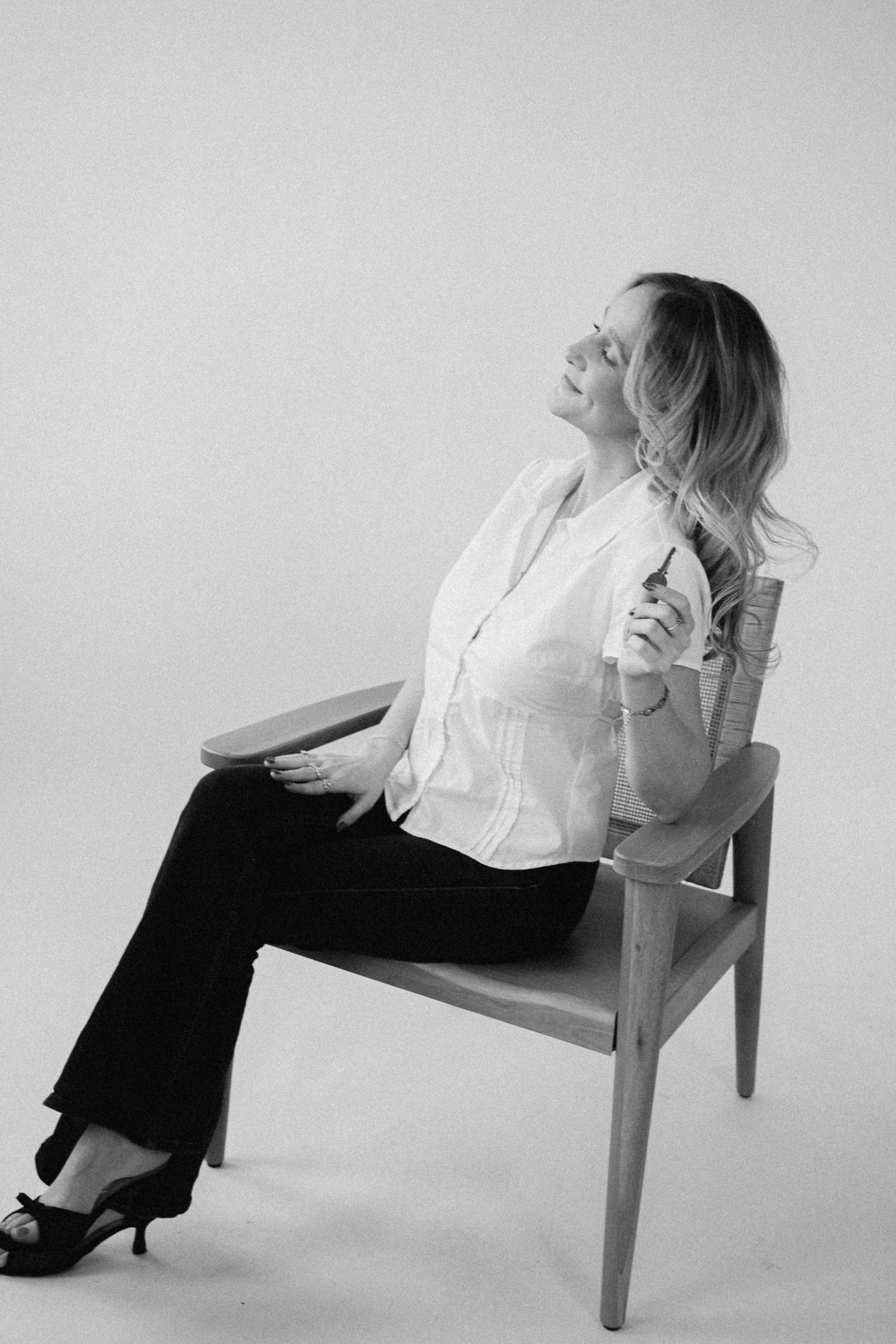 A black and white photo series showing a person in white top and black pants posing expressively on a chair.