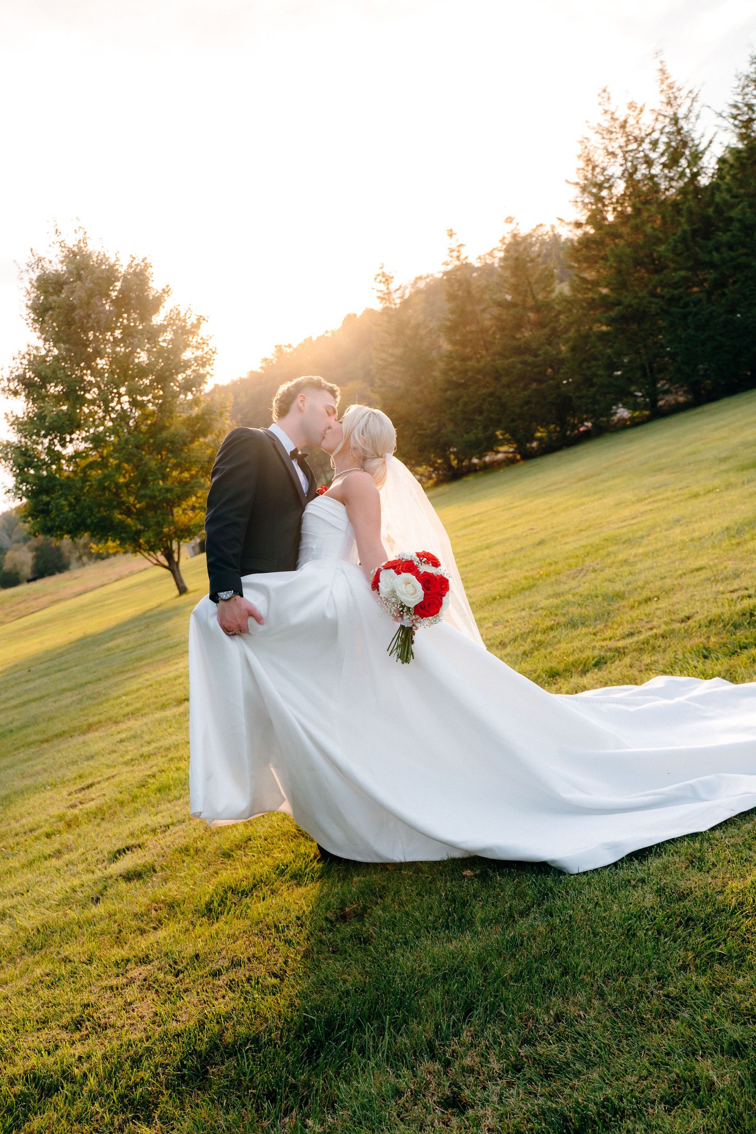 Romantic sunset wedding photos of a couple in a grassy field with flowing white dress and veil.