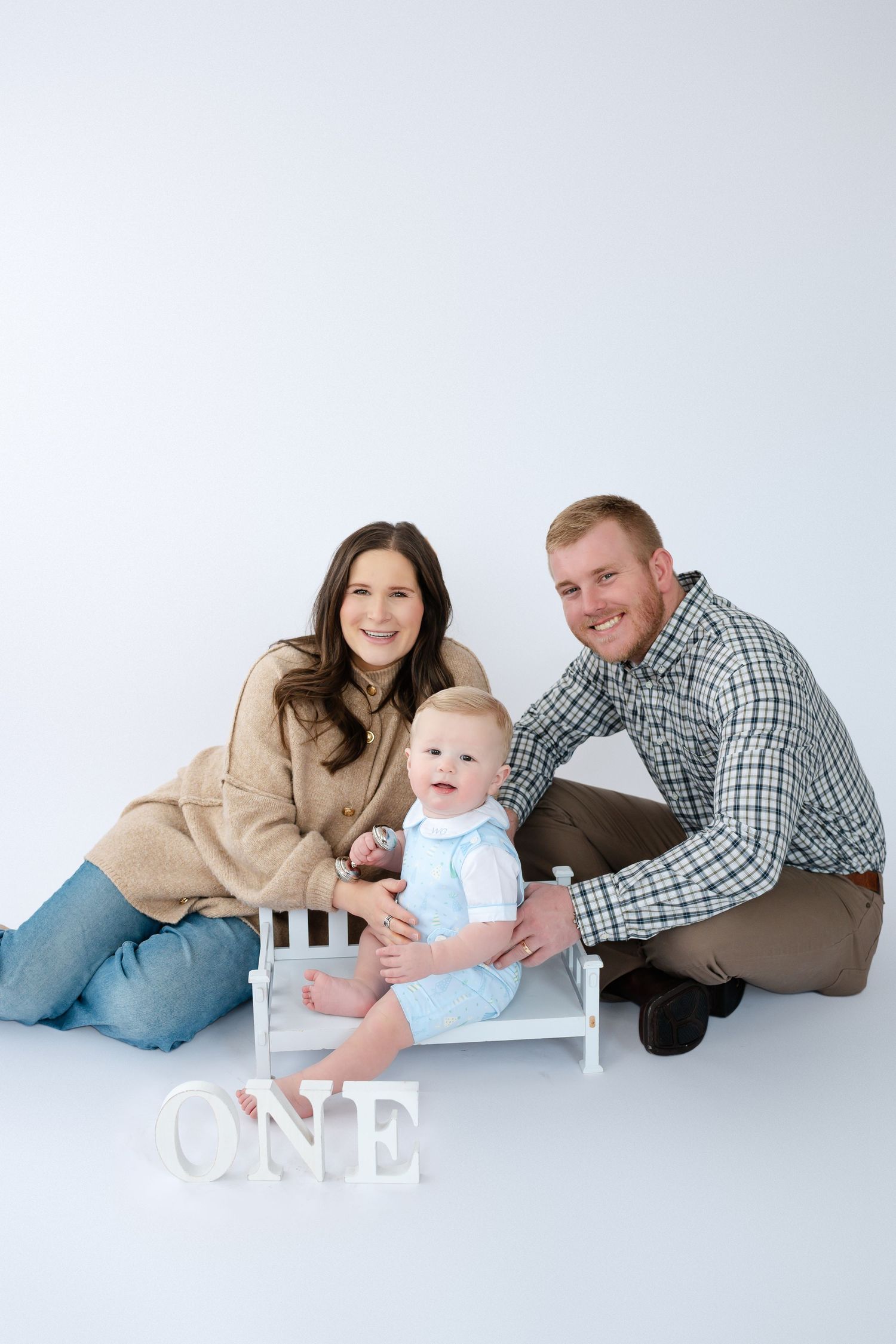 Family portrait progression showing parents and baby on white backdrop in matching casual outfits.