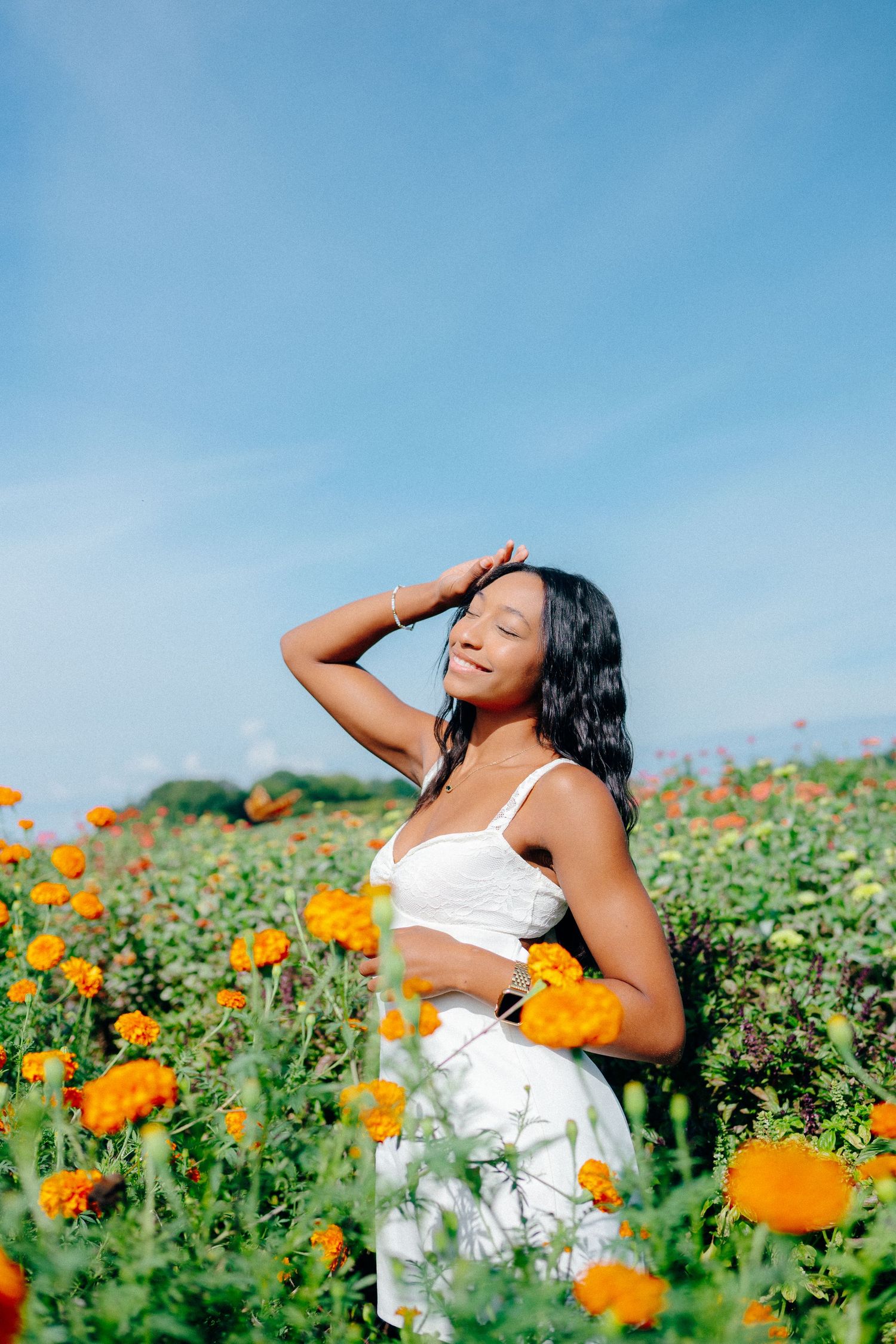 Artistic portrait in a field of orange poppies against bright blue sky.