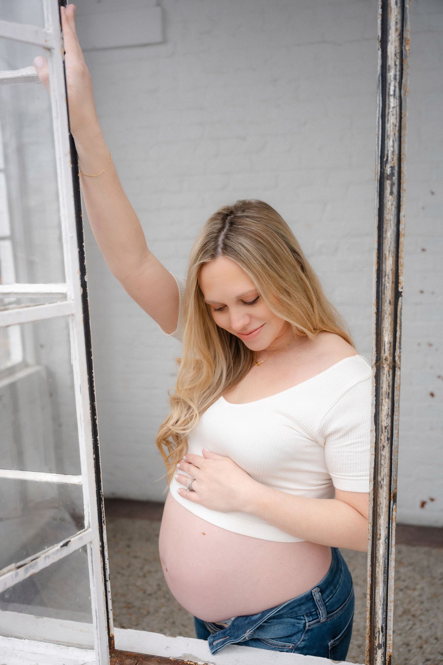Maternity photo shoot in white interior with large windows.