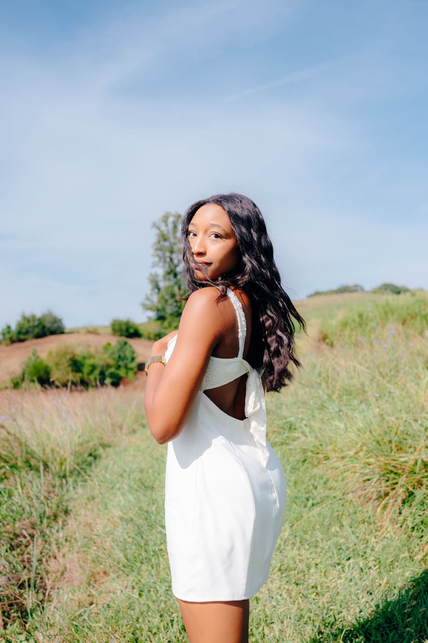 Candid summer photoshoot in a grassy field under blue skies.
