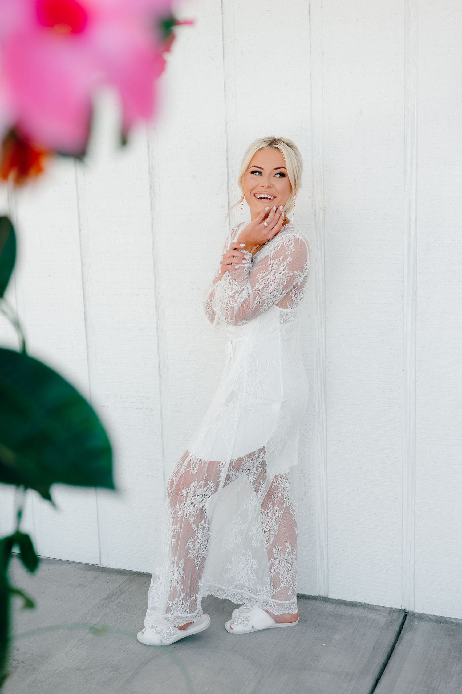 A flower girl in a white lace dress plays on a white porch.