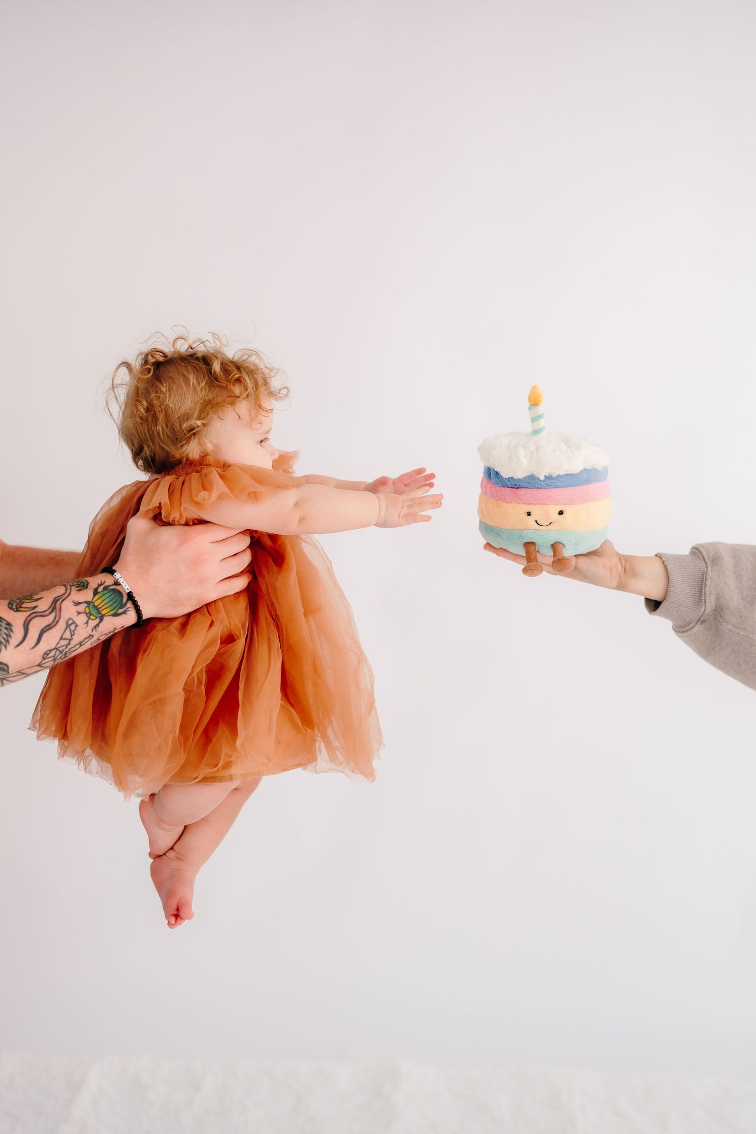 Sequence showing baby in peach dress reaching for birthday cake prop.