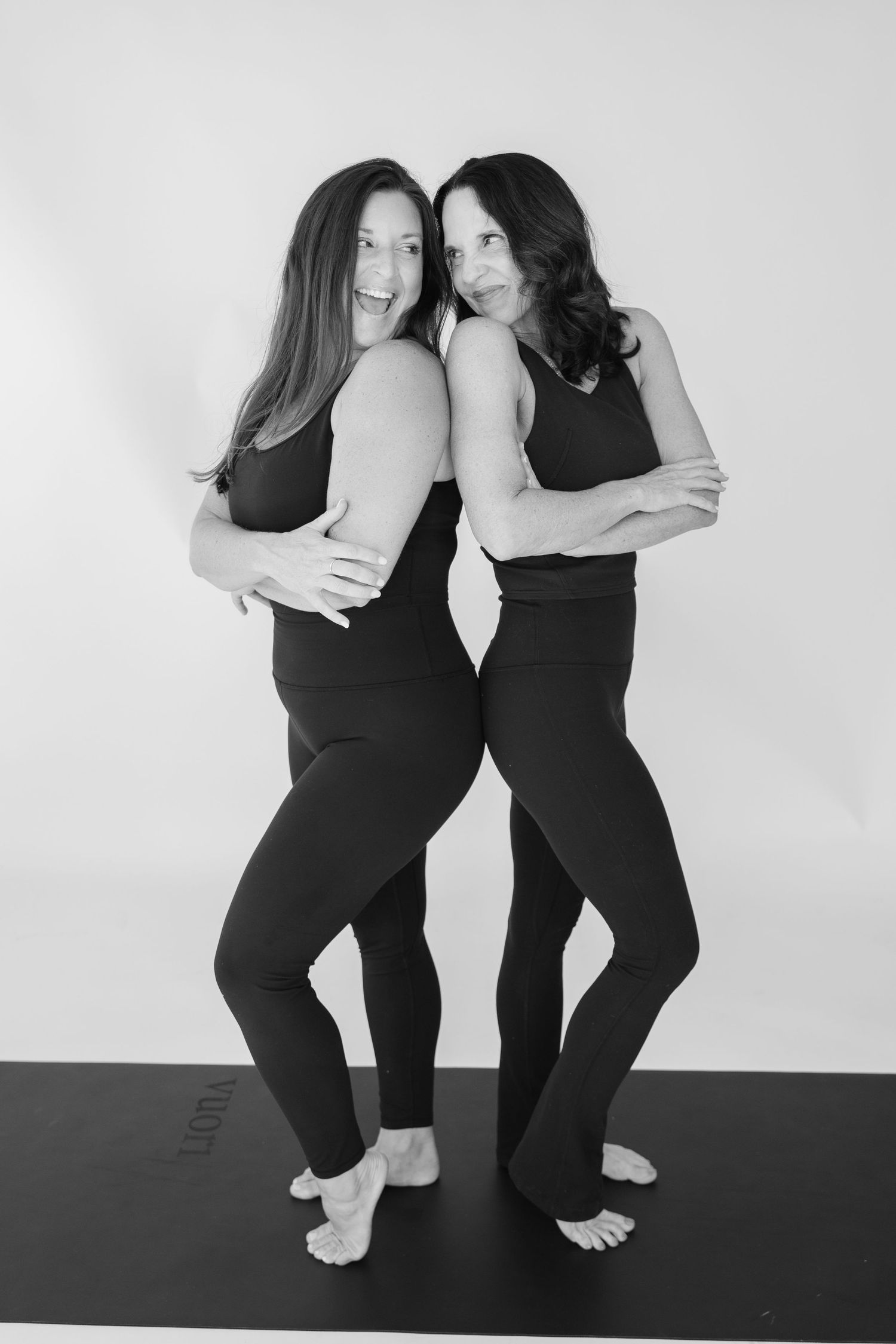 Black and white photos of two people demonstrating partner yoga poses on exercise mat.