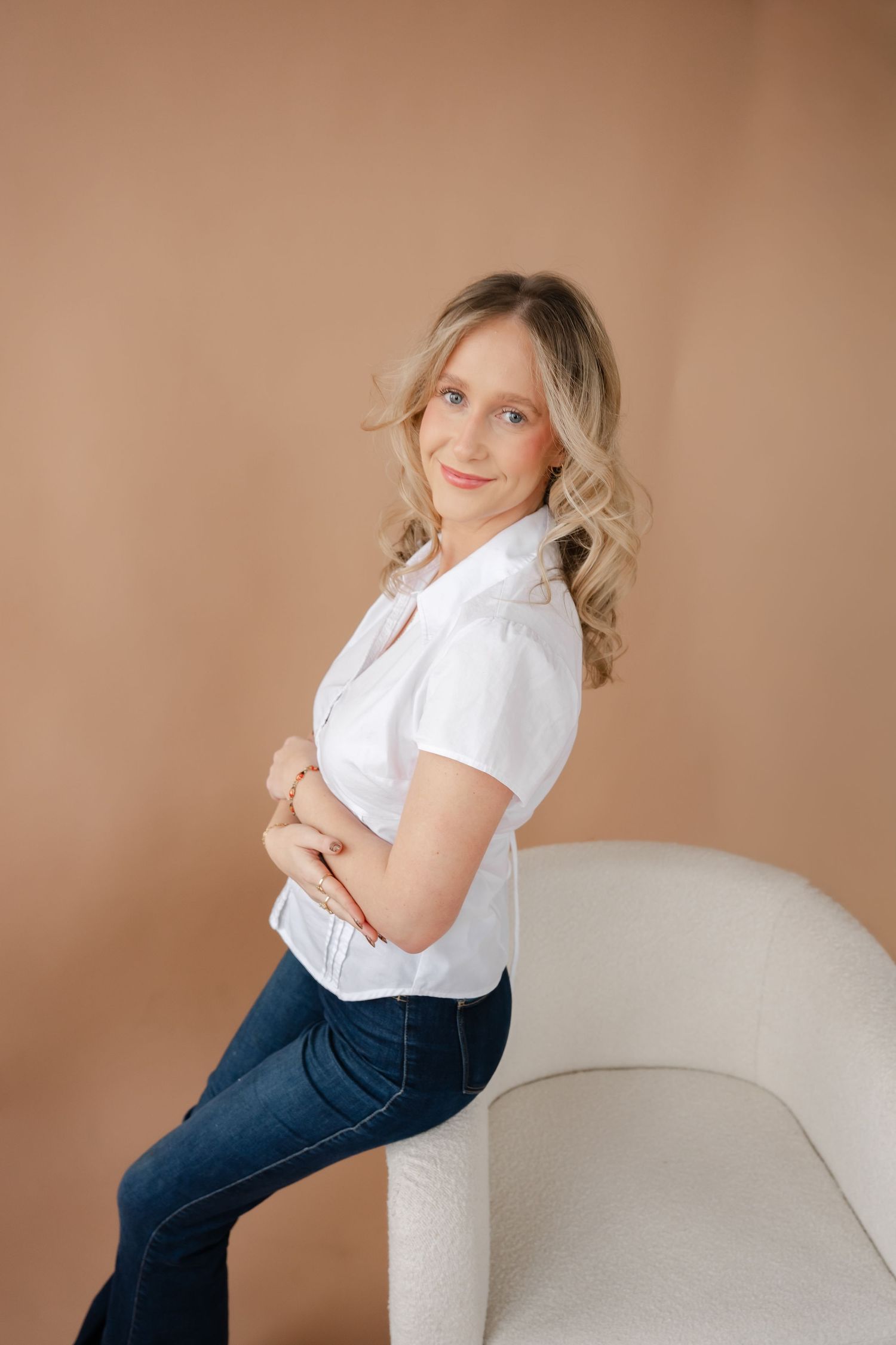Professional lifestyle portrait series showing casual white top and jeans against neutral beige backdrop.