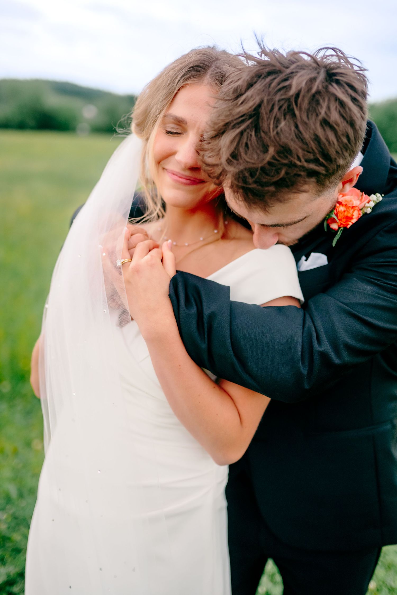 A tender moment between newlyweds embracing in a sunny field.