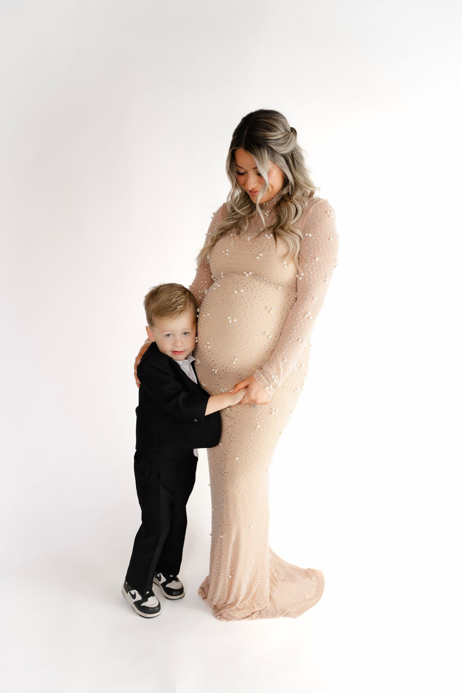 Sweet maternity photos in white studio with young children embracing their pregnant mother.