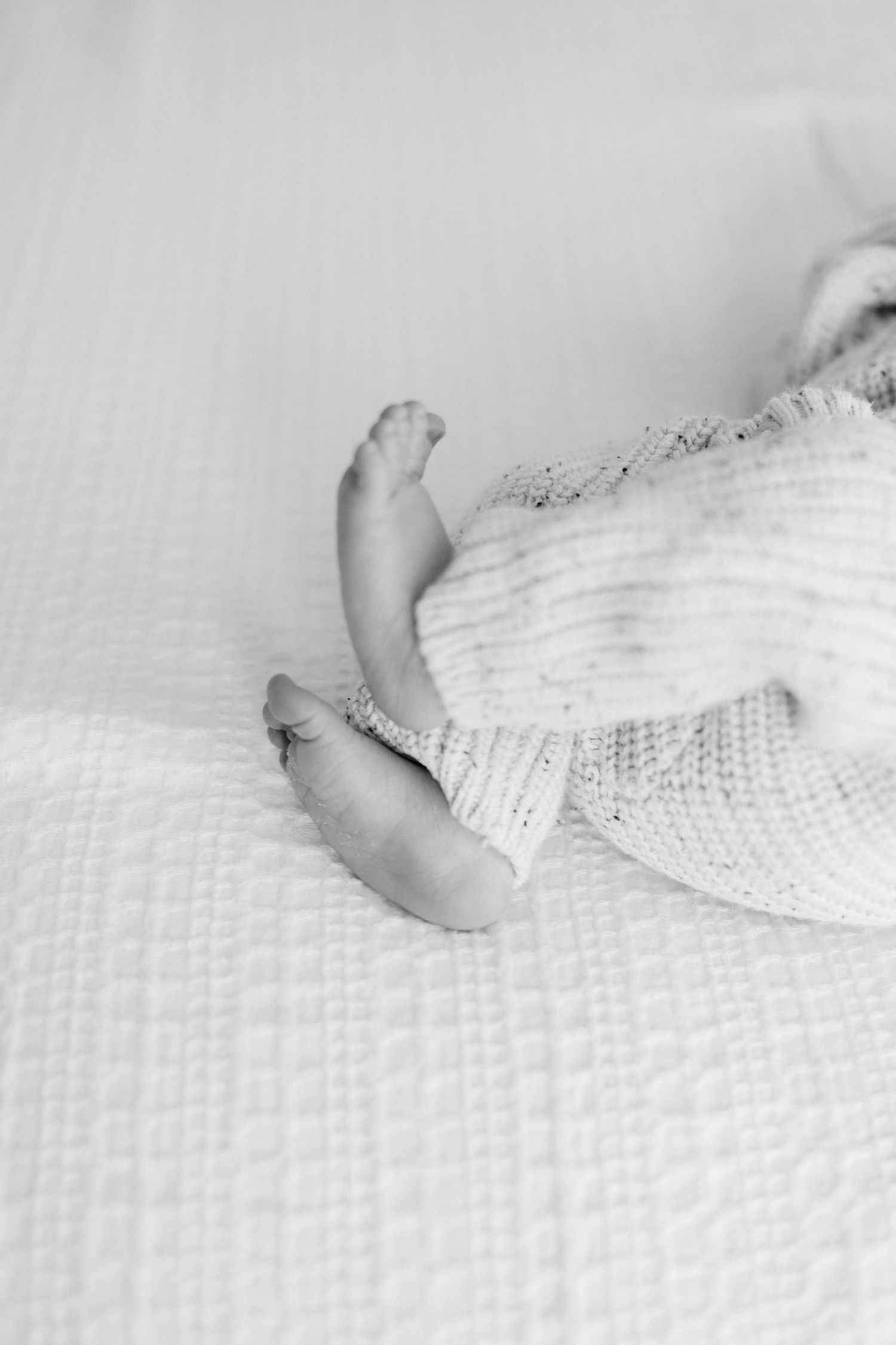 Close up of small feet against white textured bedding.